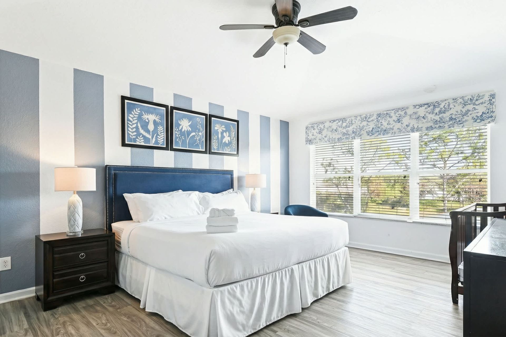 Spacious master suite with king bed, crib, natural light, and calming decor.