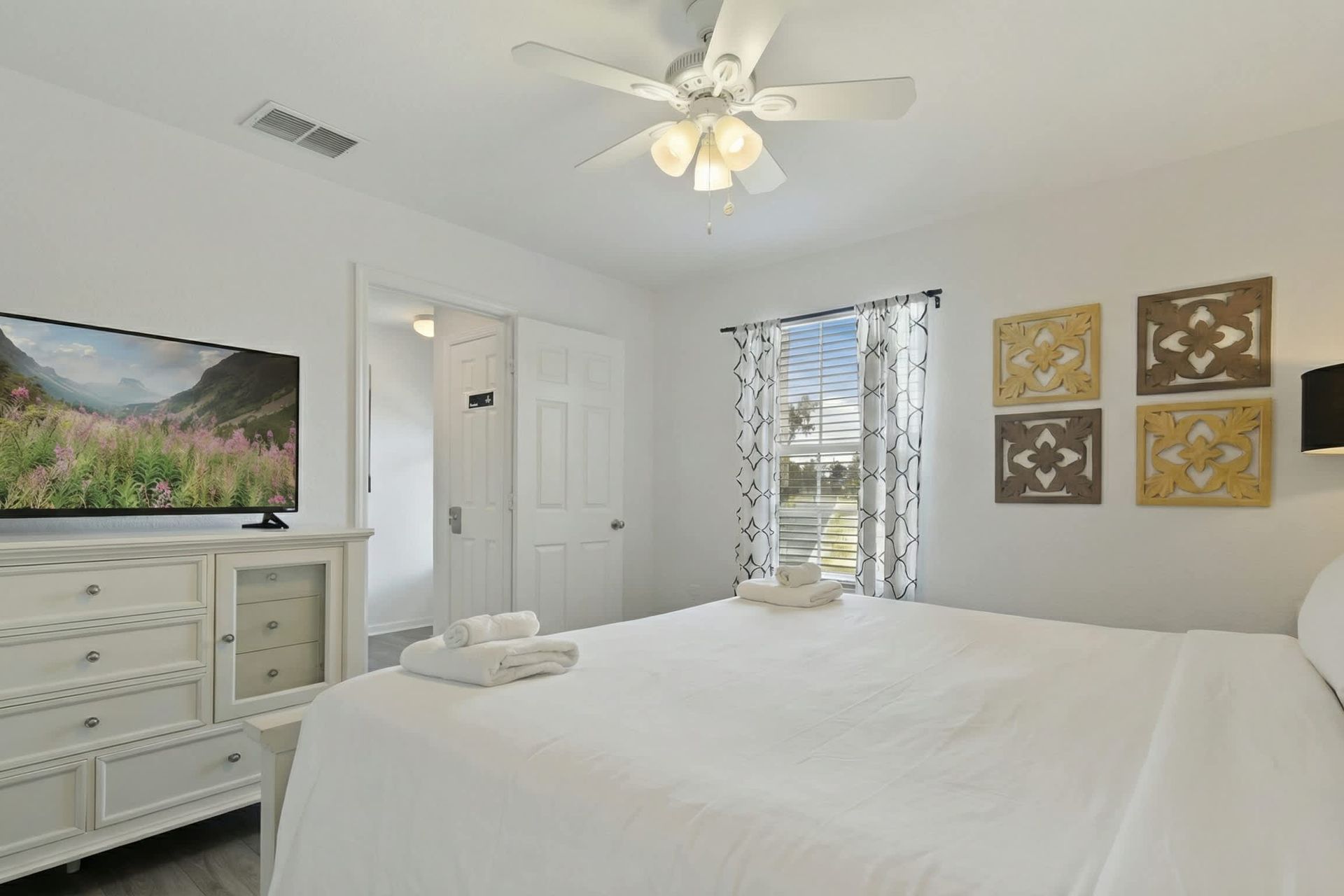 Relax in this serene king bedroom with modern decor, TV, and natural light views.