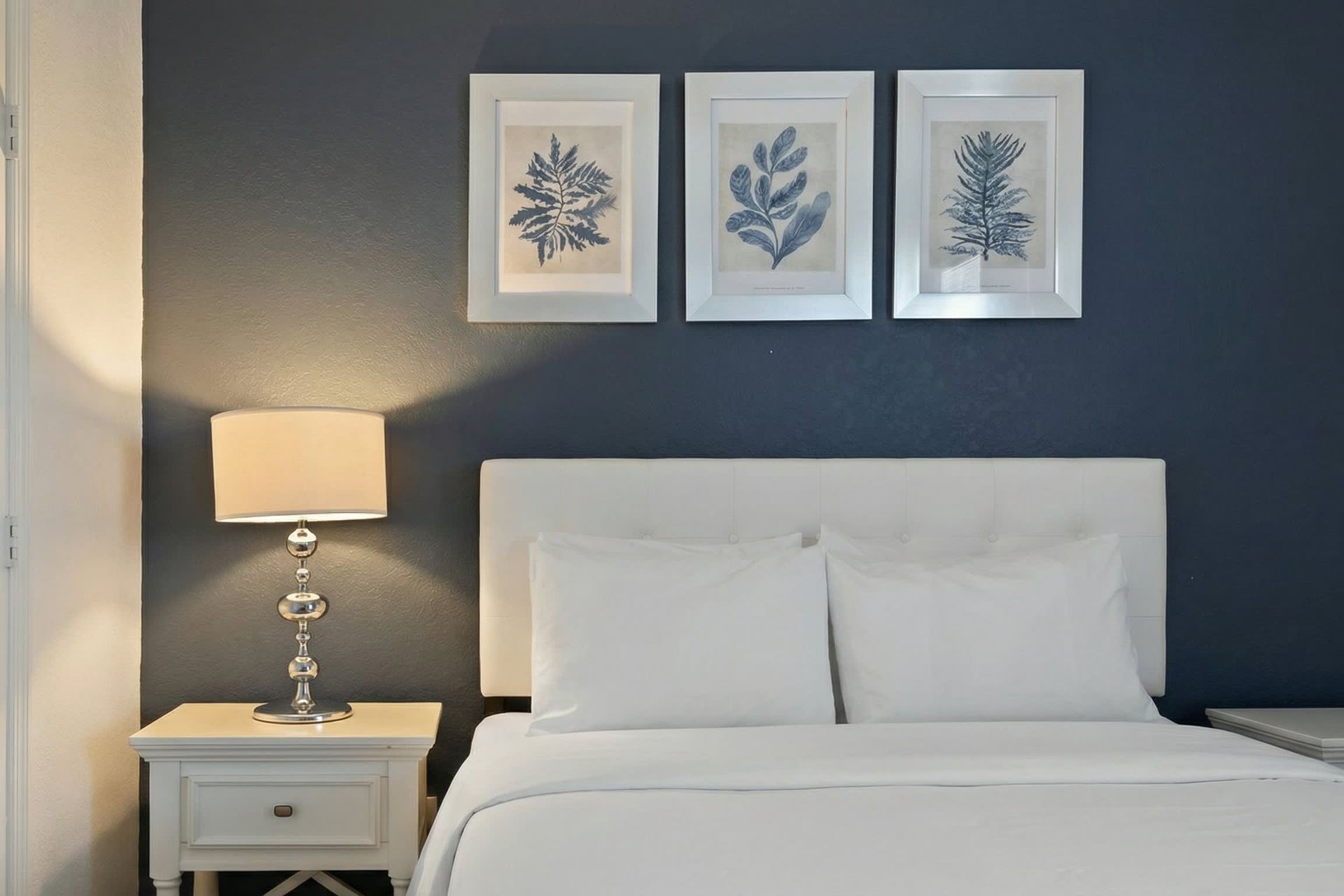 Elegant navy-accented queen room with plush bedding and serene, modern décor.