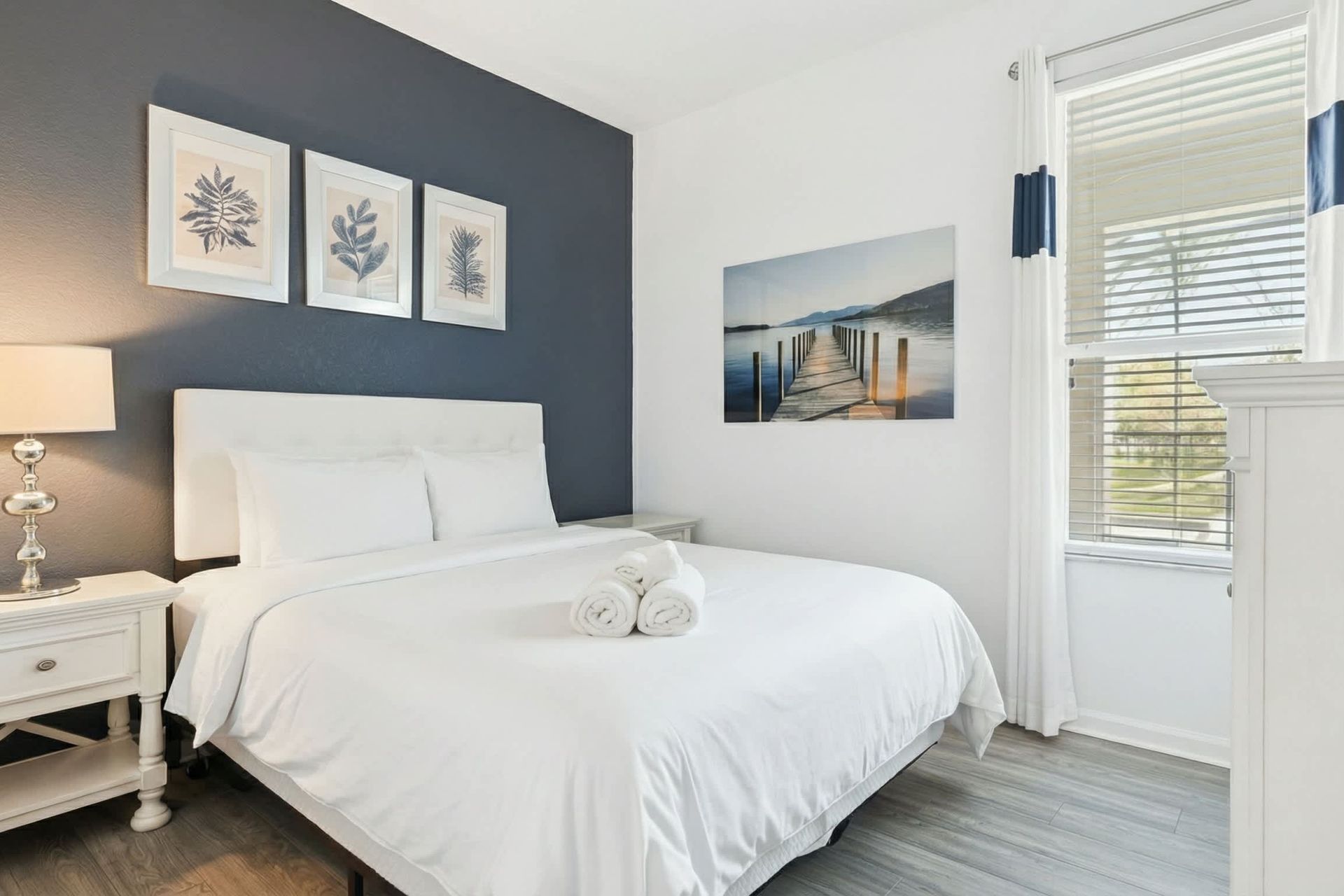 Cozy queen bedroom with chic navy accents, flat-screen TV, and peaceful ambiance.