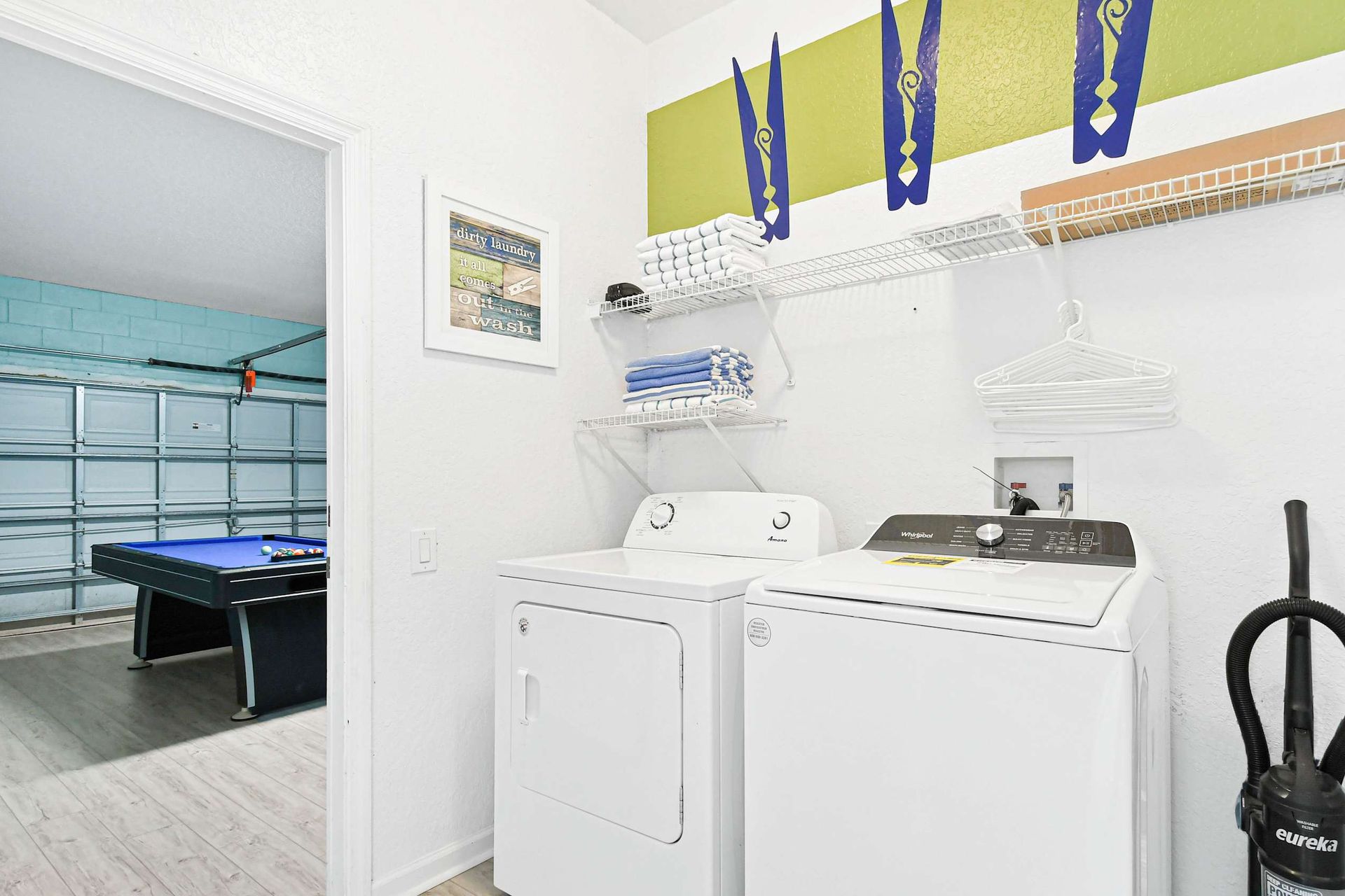 Laundry room with modern appliances adjacent to a vibrant game room with pool table.