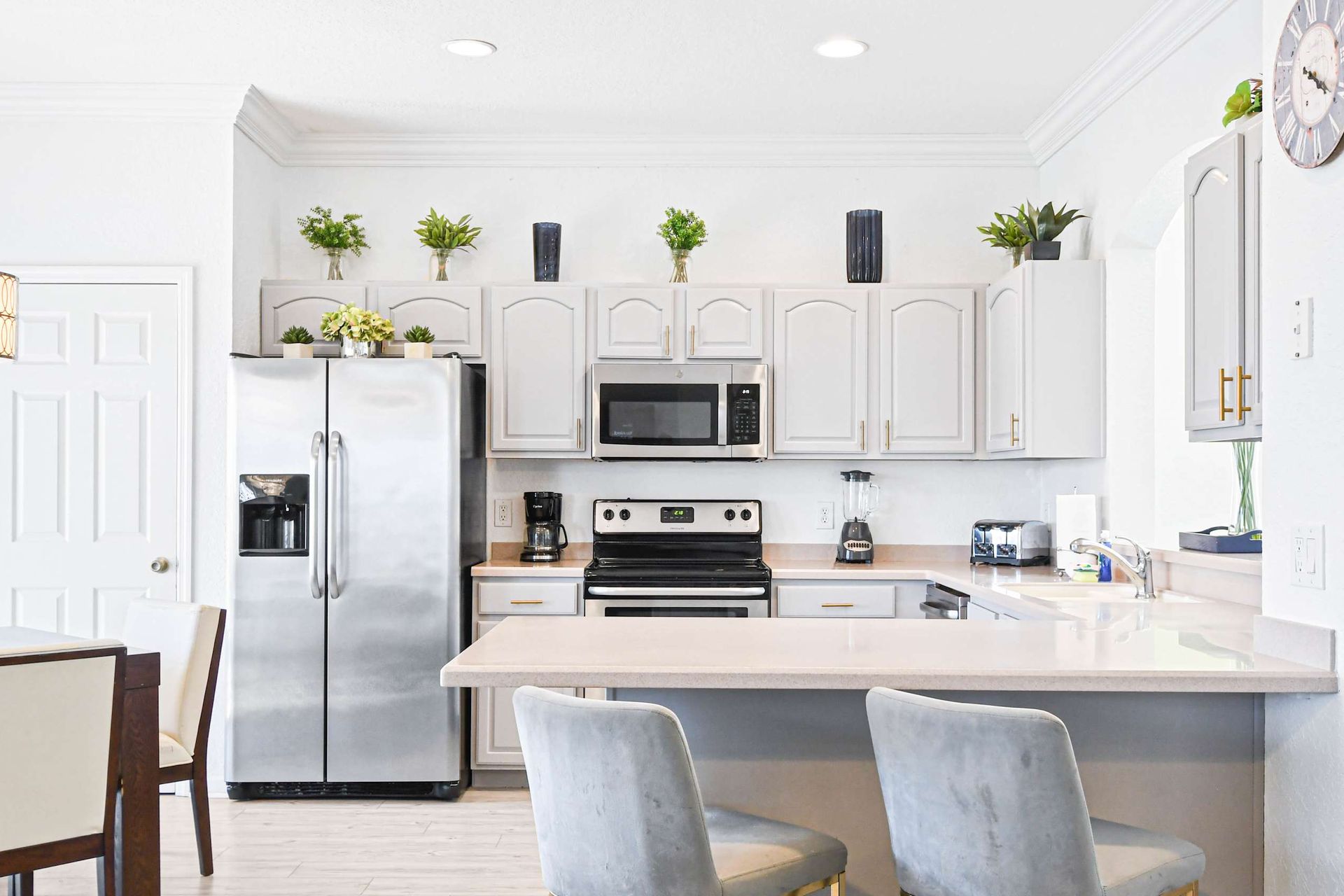 Modern kitchen with stainless steel appliances, breakfast bar, and bright decor.