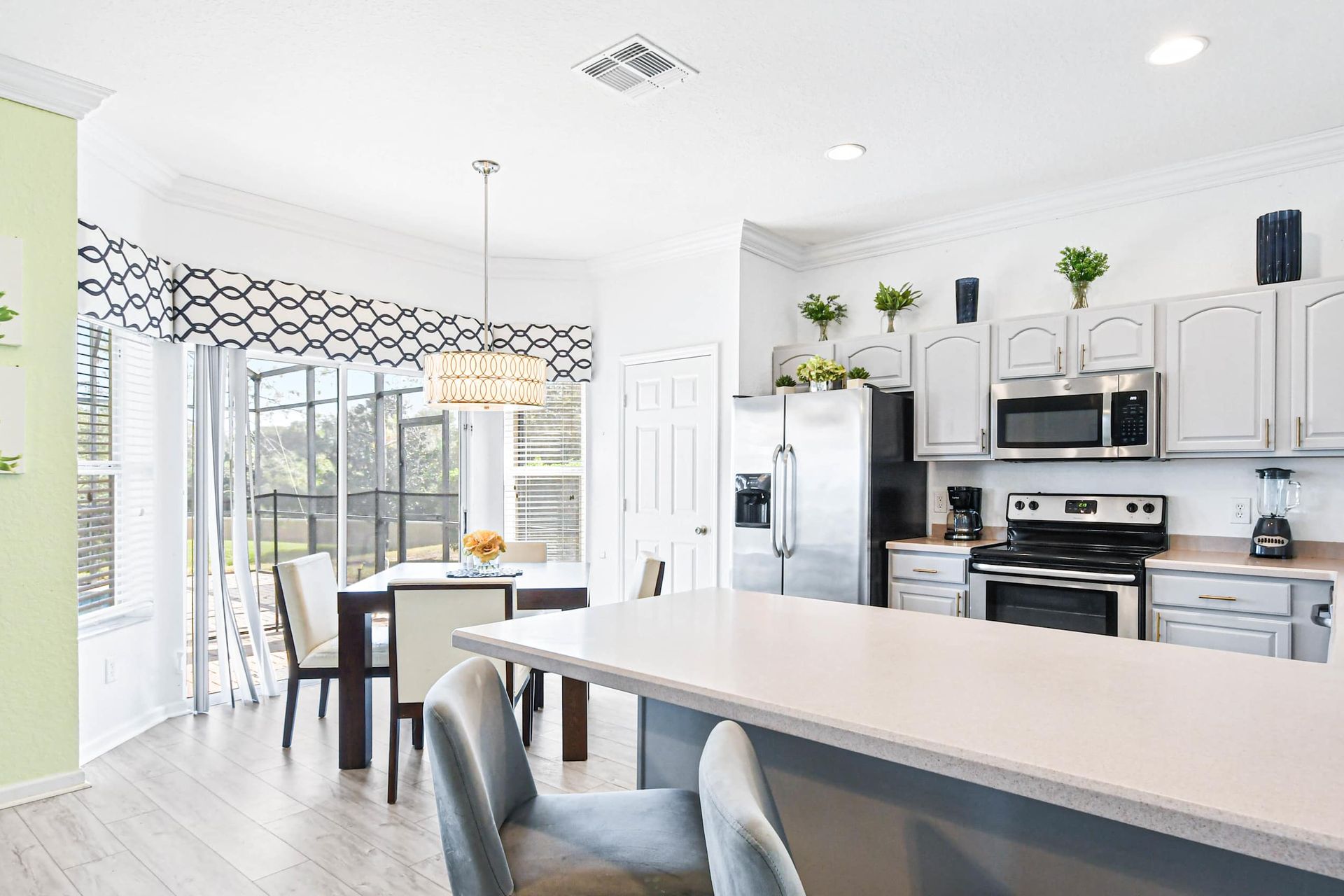Bright open kitchen with breakfast bar, stainless appliances, and poolside views.