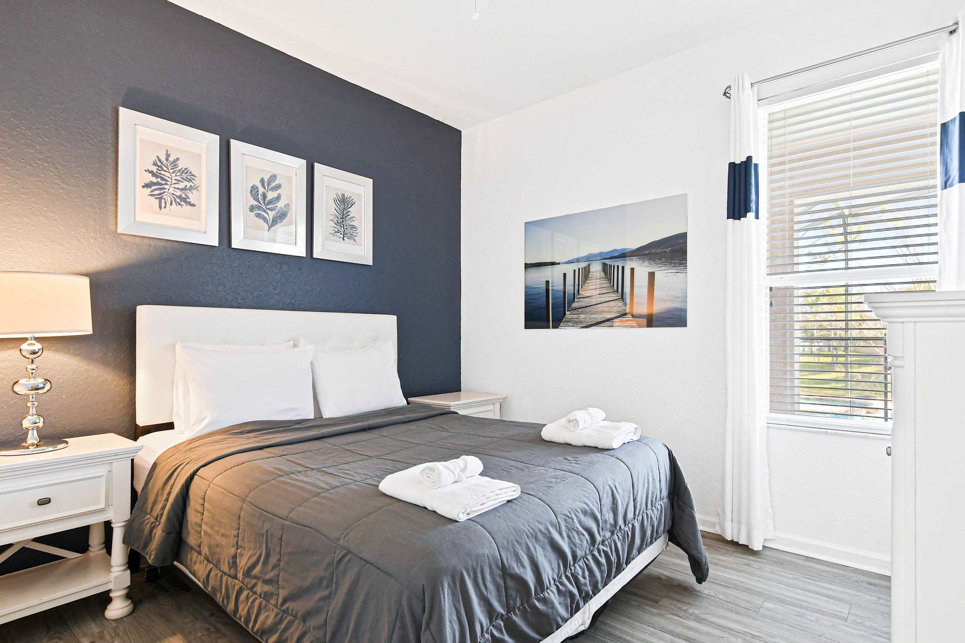 Cozy queen bedroom with chic navy accents, flat-screen TV, and peaceful ambiance.