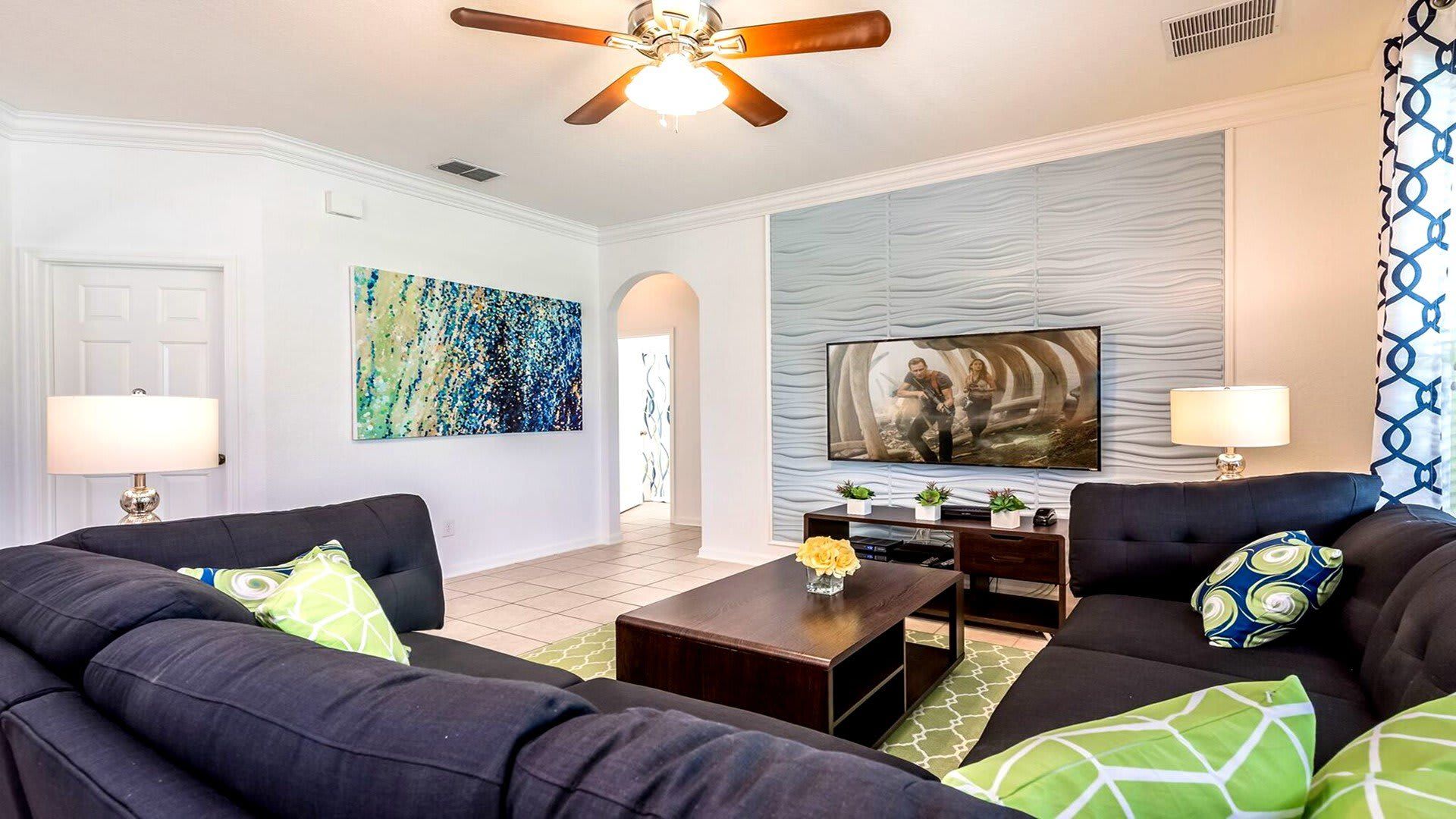 Vibrant living room with large sectional, flat-screen TV, and bold modern art.
