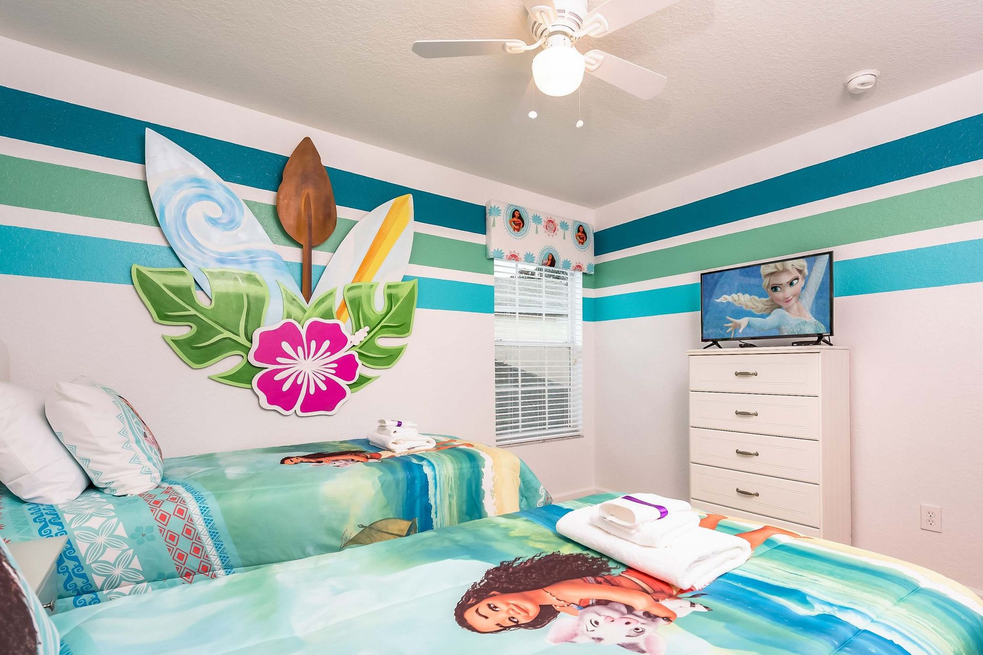 Colorful Moana-themed twin room with TV, perfect for fun and cozy nights.