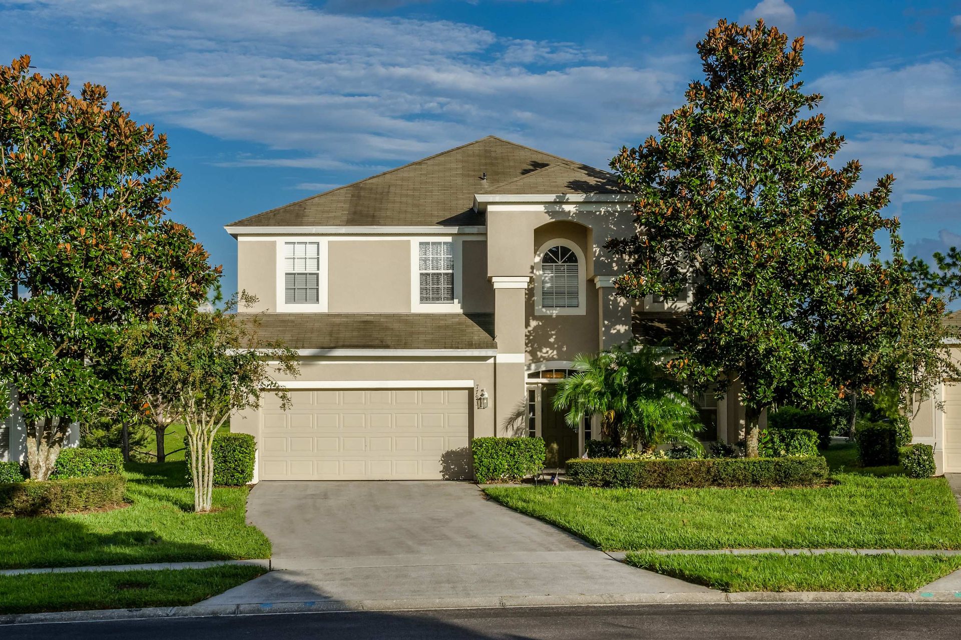 Beautiful two-story vacation home with a manicured lawn, private driveway, and lush landscaping.