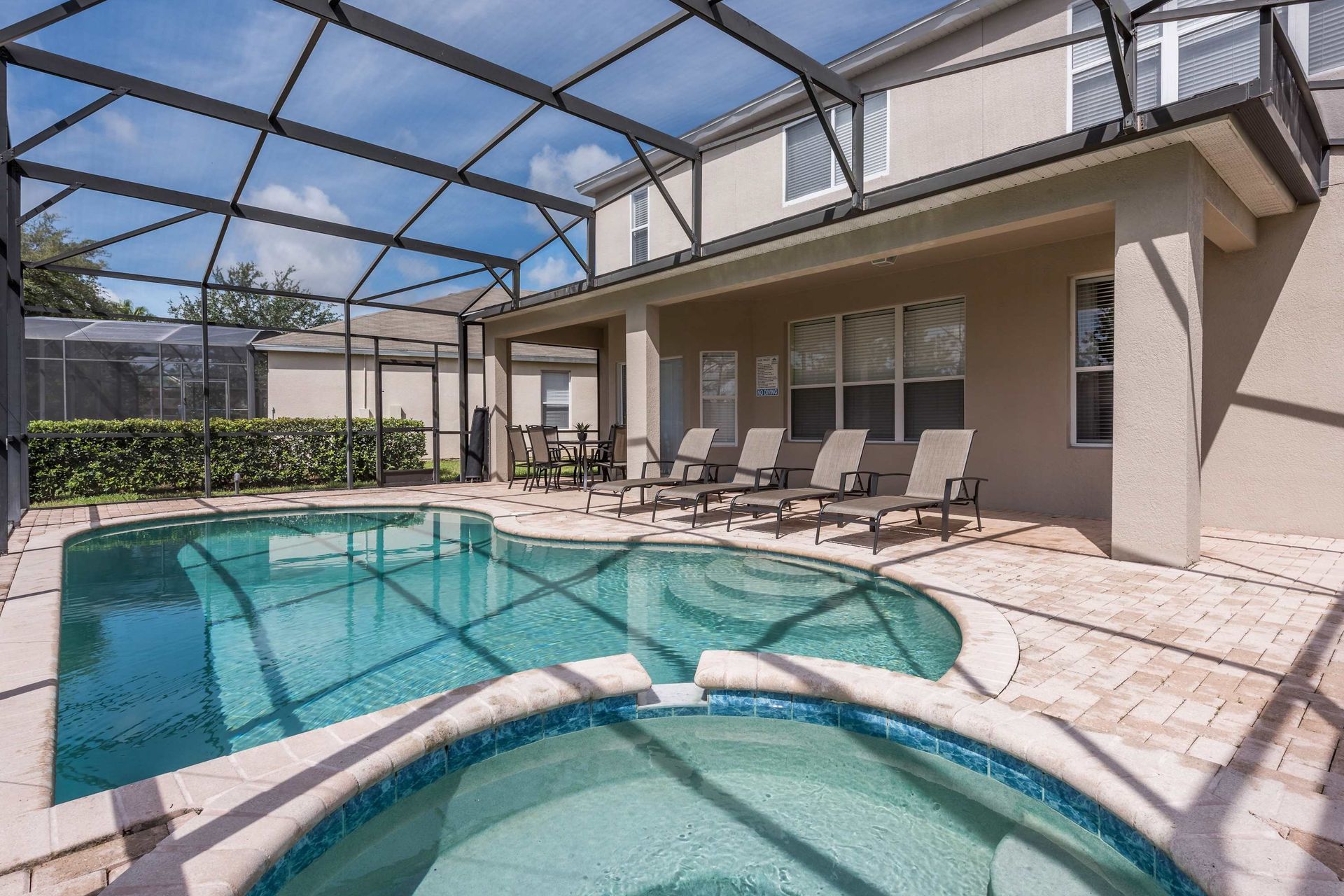 Private screened pool and spa with ample sun loungers and shaded patio seating.