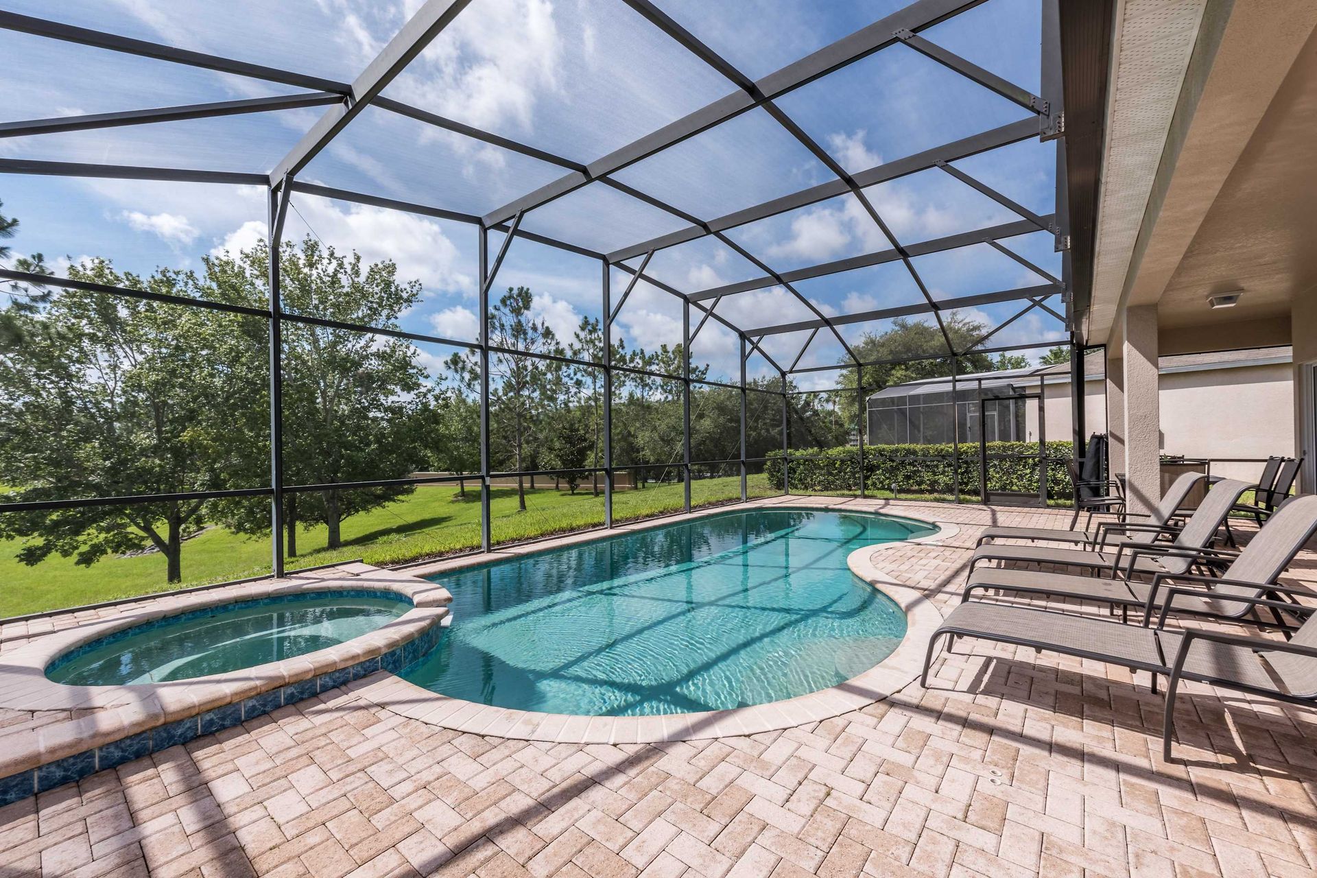 Private screened pool and spa with loungers and peaceful green views.