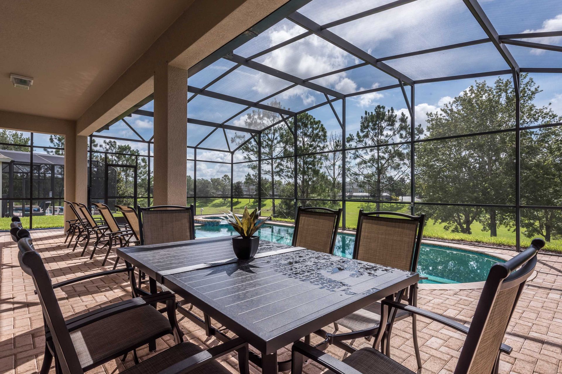 Covered patio with poolside dining and scenic views of lush greenery beyond.