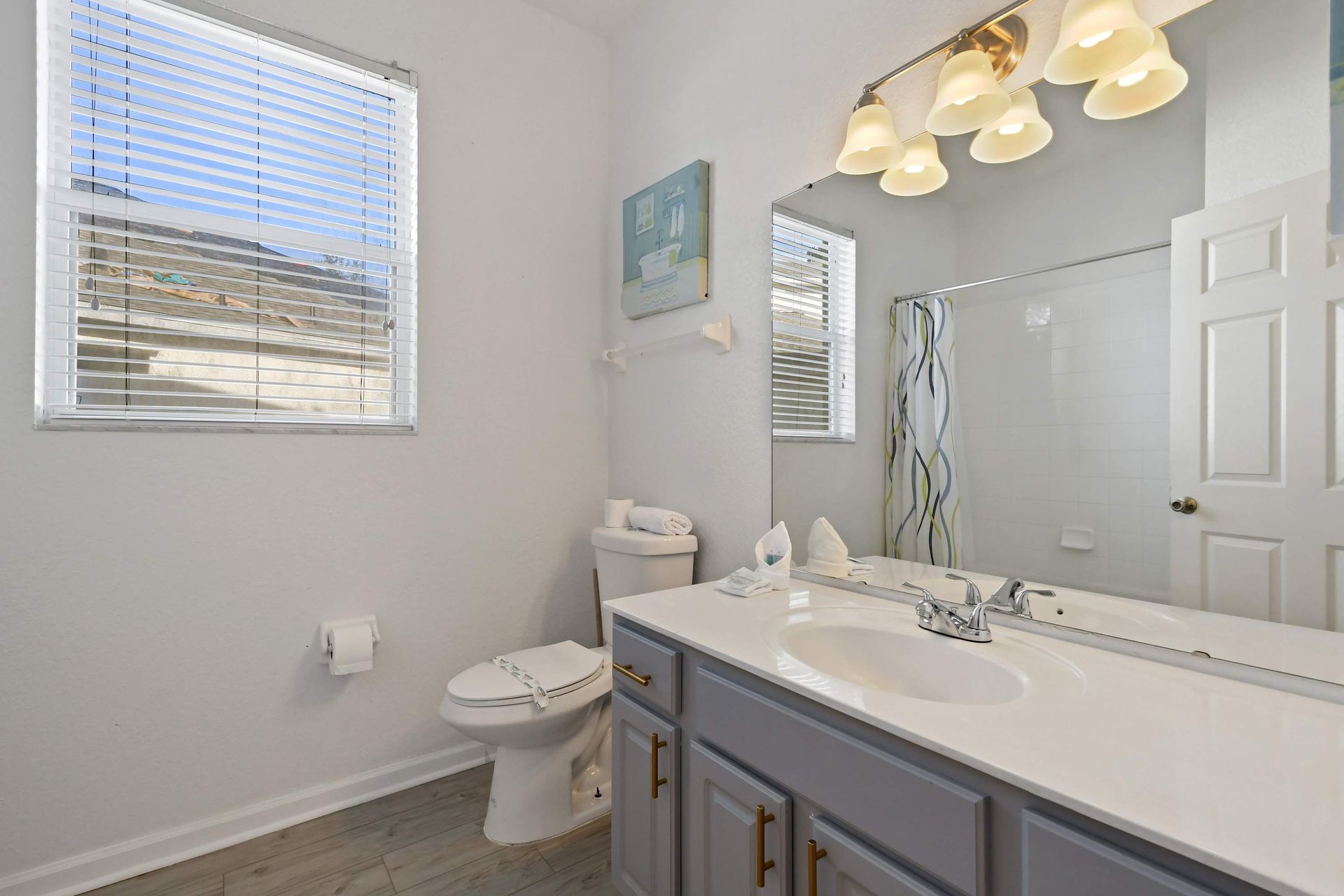 Bright, modern bathroom with double vanity, large mirror, and shower-tub combo.