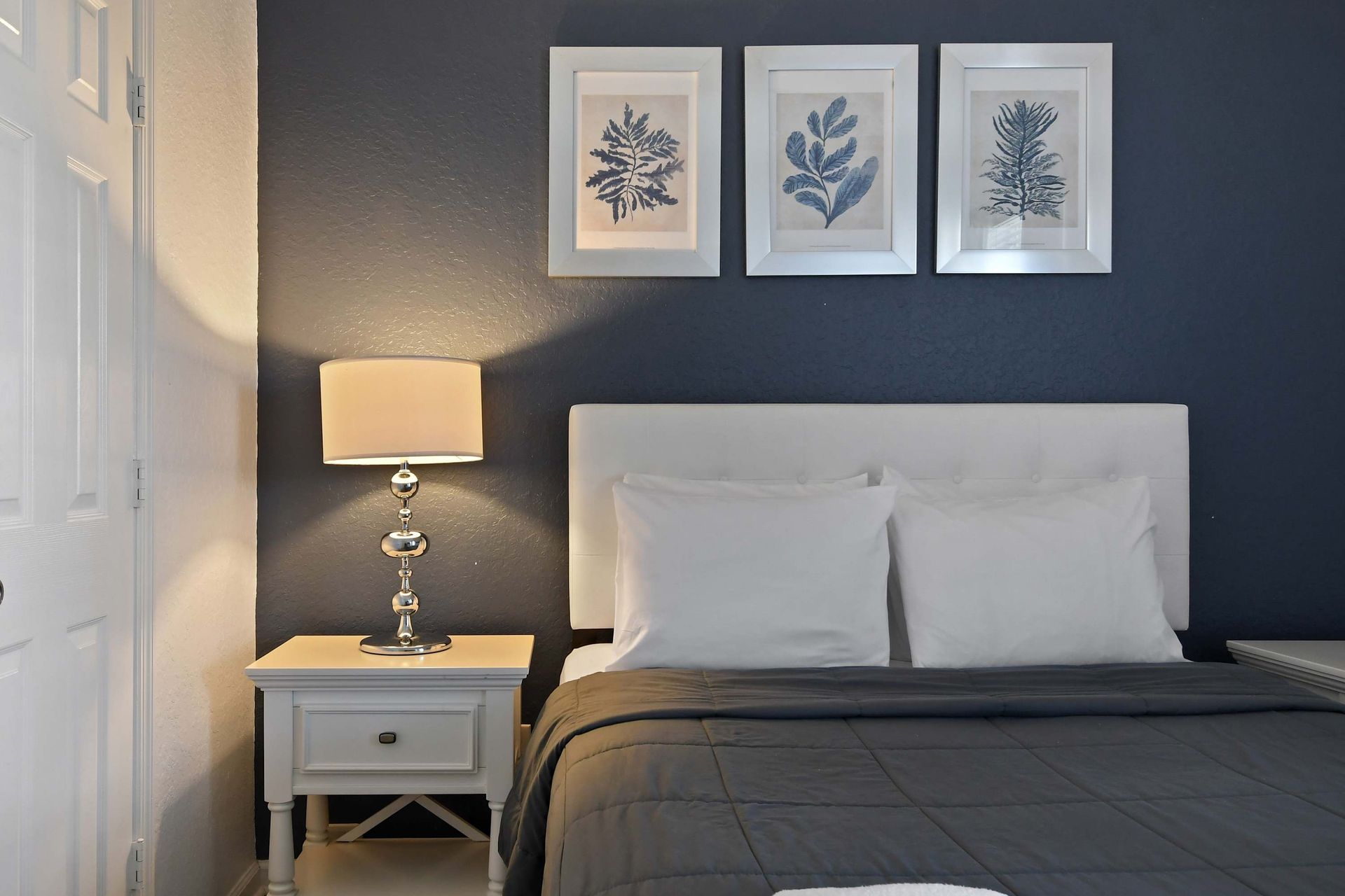 Elegant navy-accented queen room with plush bedding and serene, modern décor.