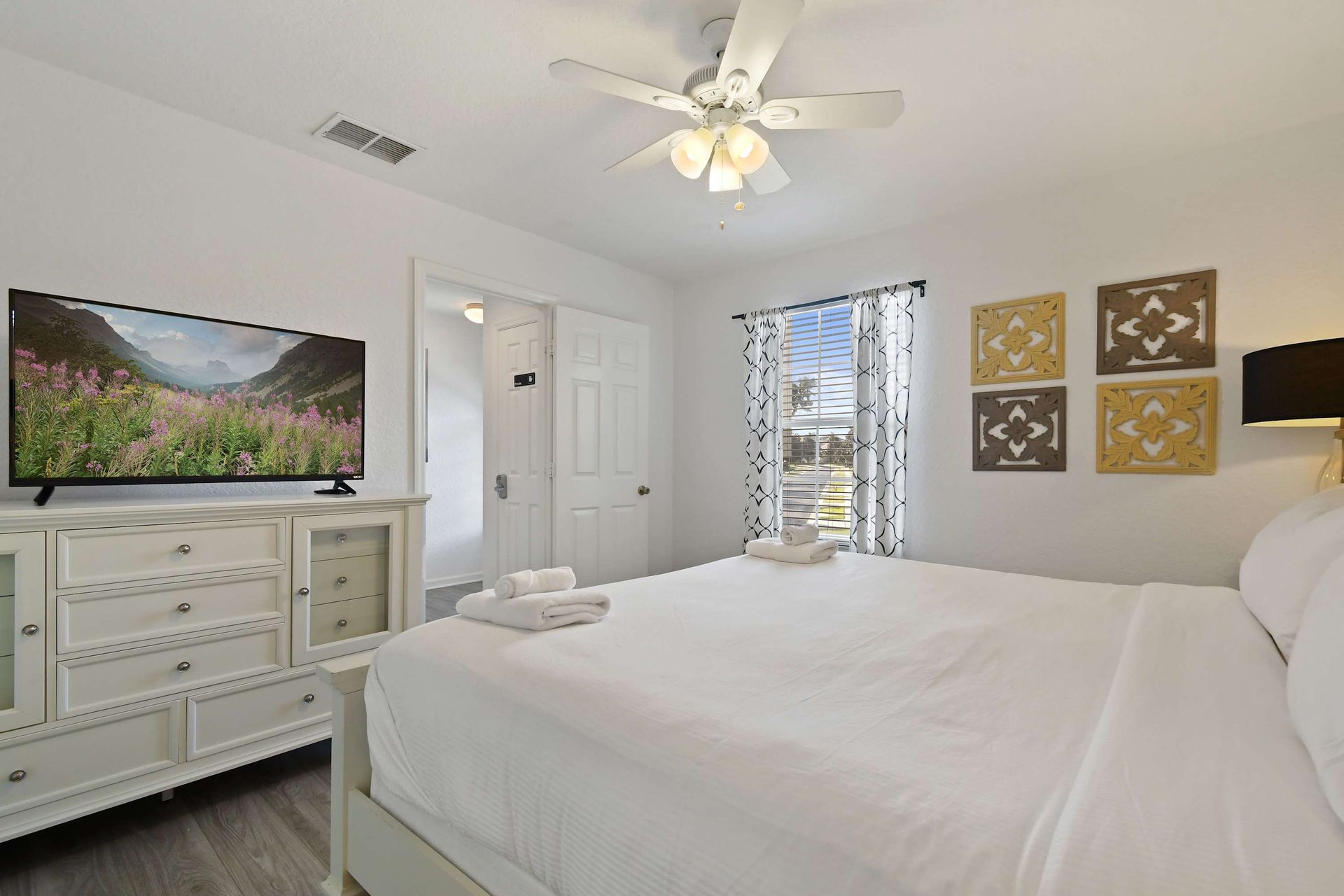 Relax in this serene king bedroom with modern decor, TV, and natural light views.