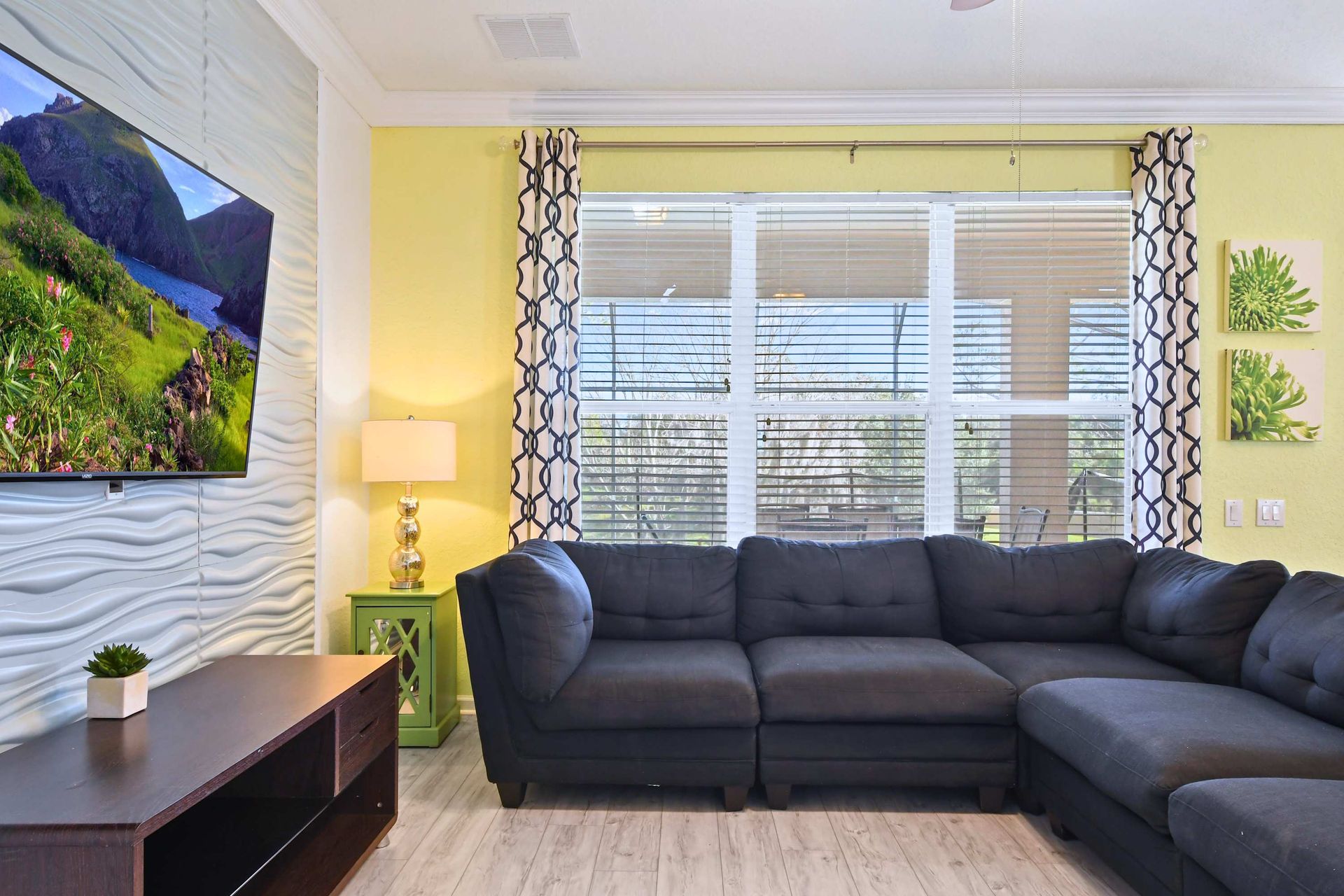 Cozy family room with plush sectional, large TV, and views of the pool area.