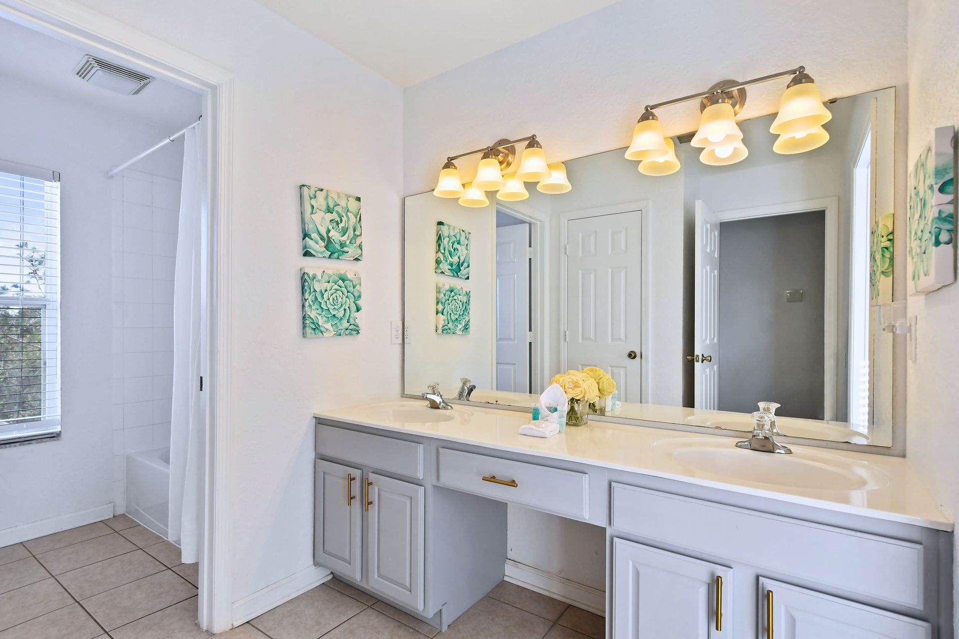 Bright bathroom with dual sinks, spacious vanity, chic lighting, and fresh decor.