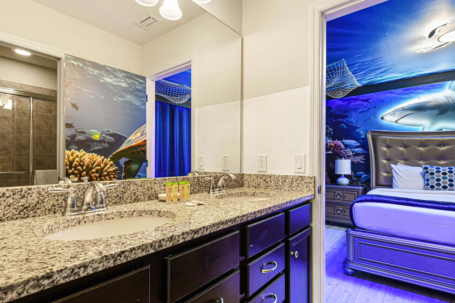 Ocean-themed bathroom with granite double vanity and tiled shower.