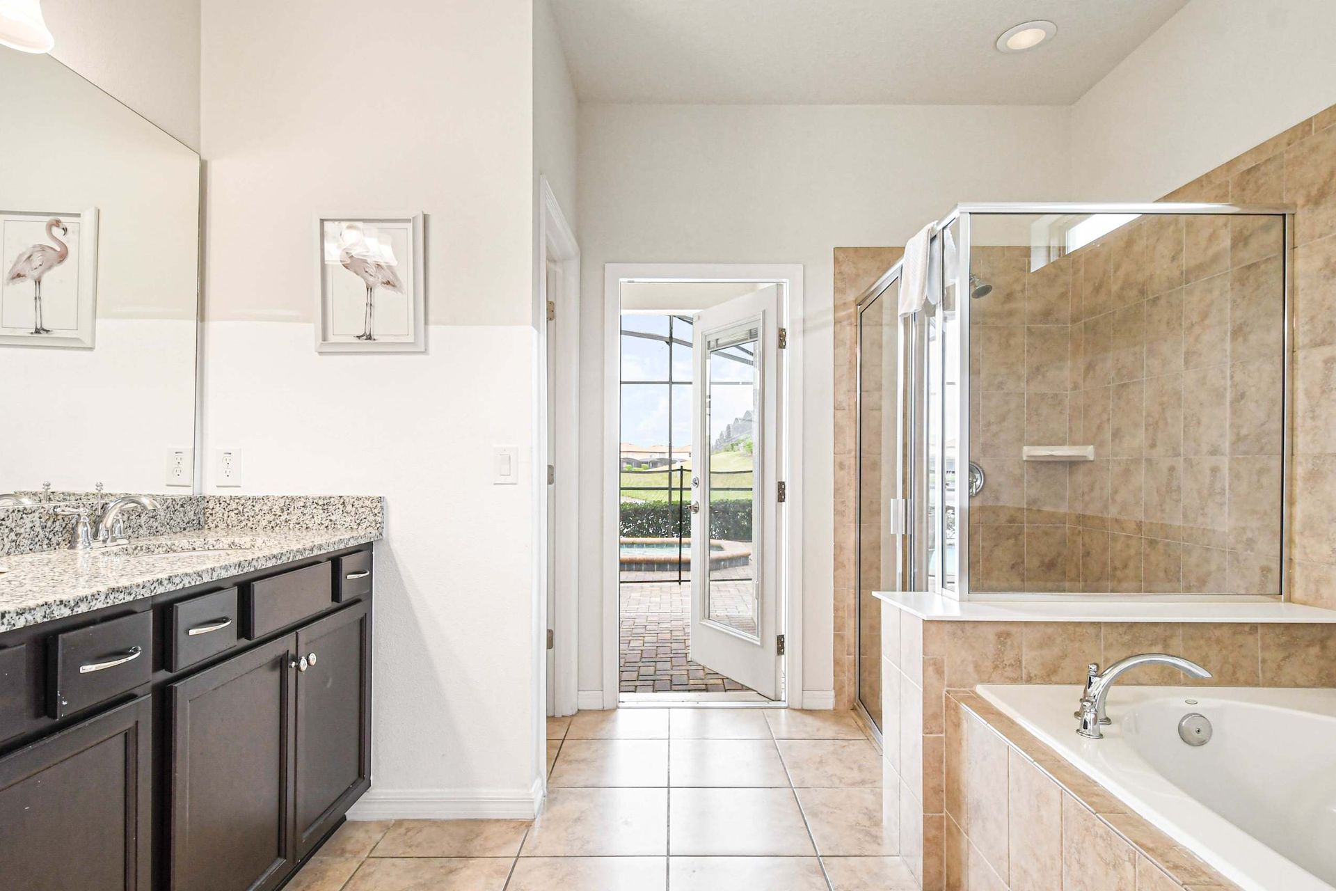 Spacious bathroom with tub, shower, and patio access to the pool.