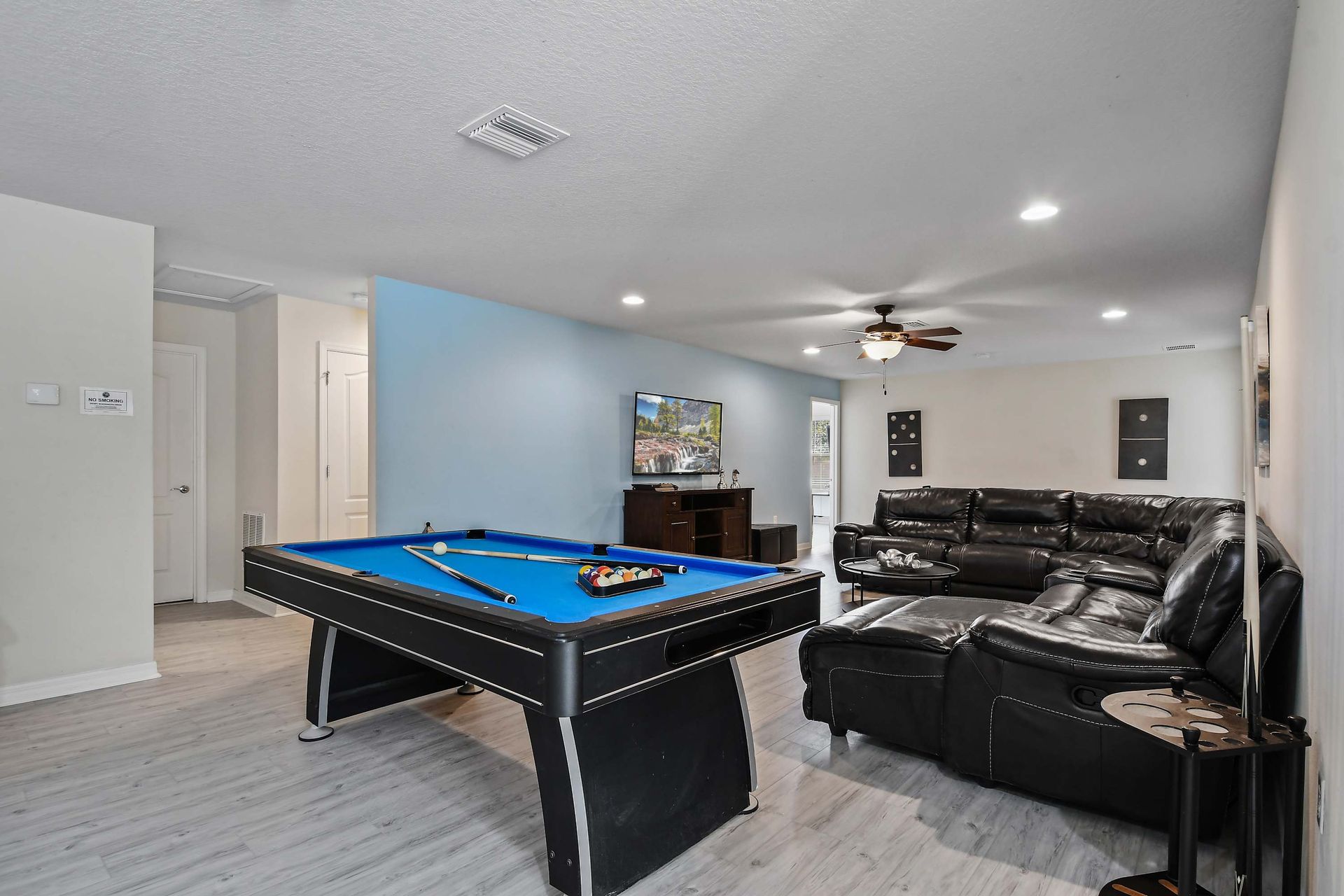 Entertainment room with a pool table, leather sectional, and large TV.