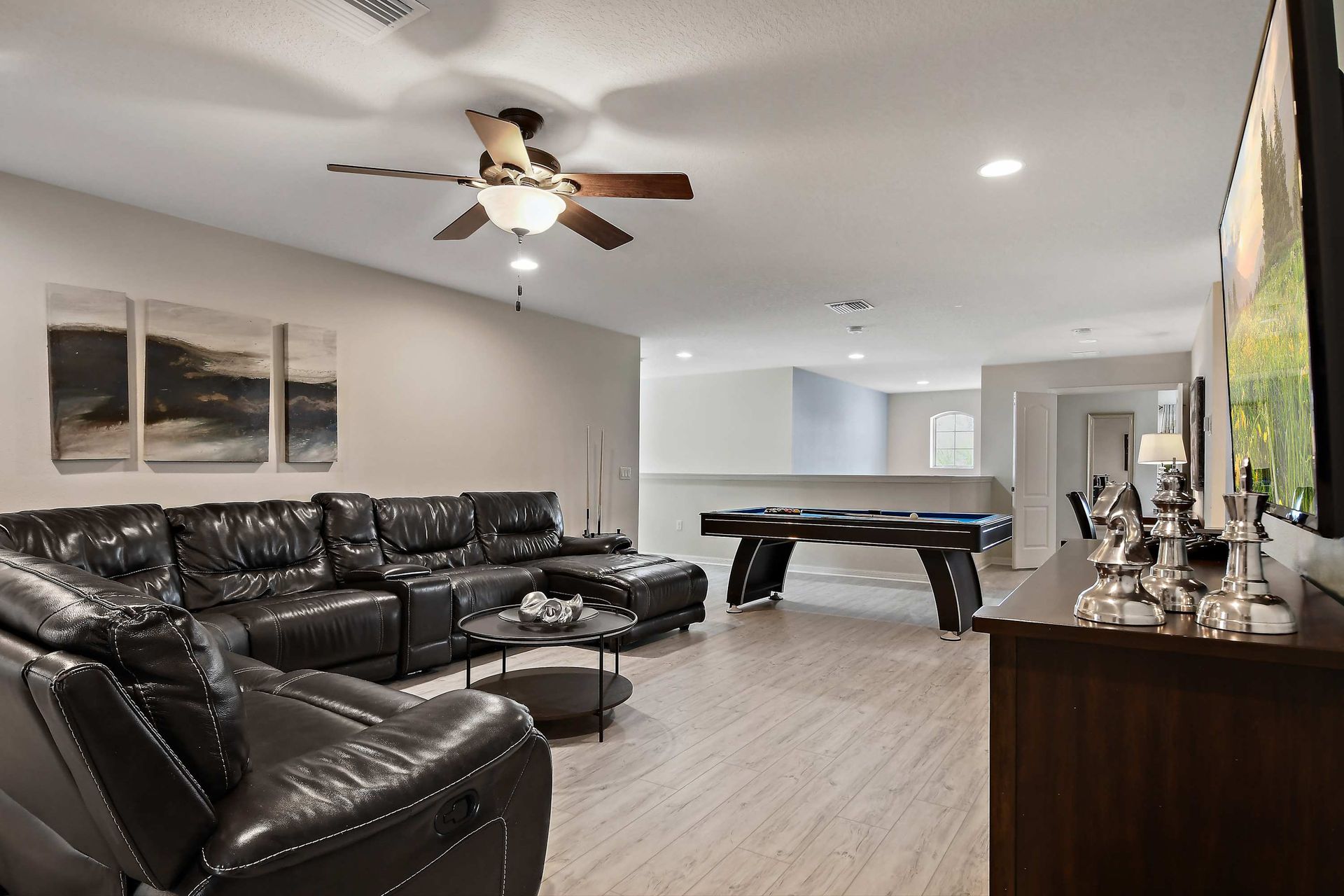 Spacious game room with pool table, leather seating, and modern decor.