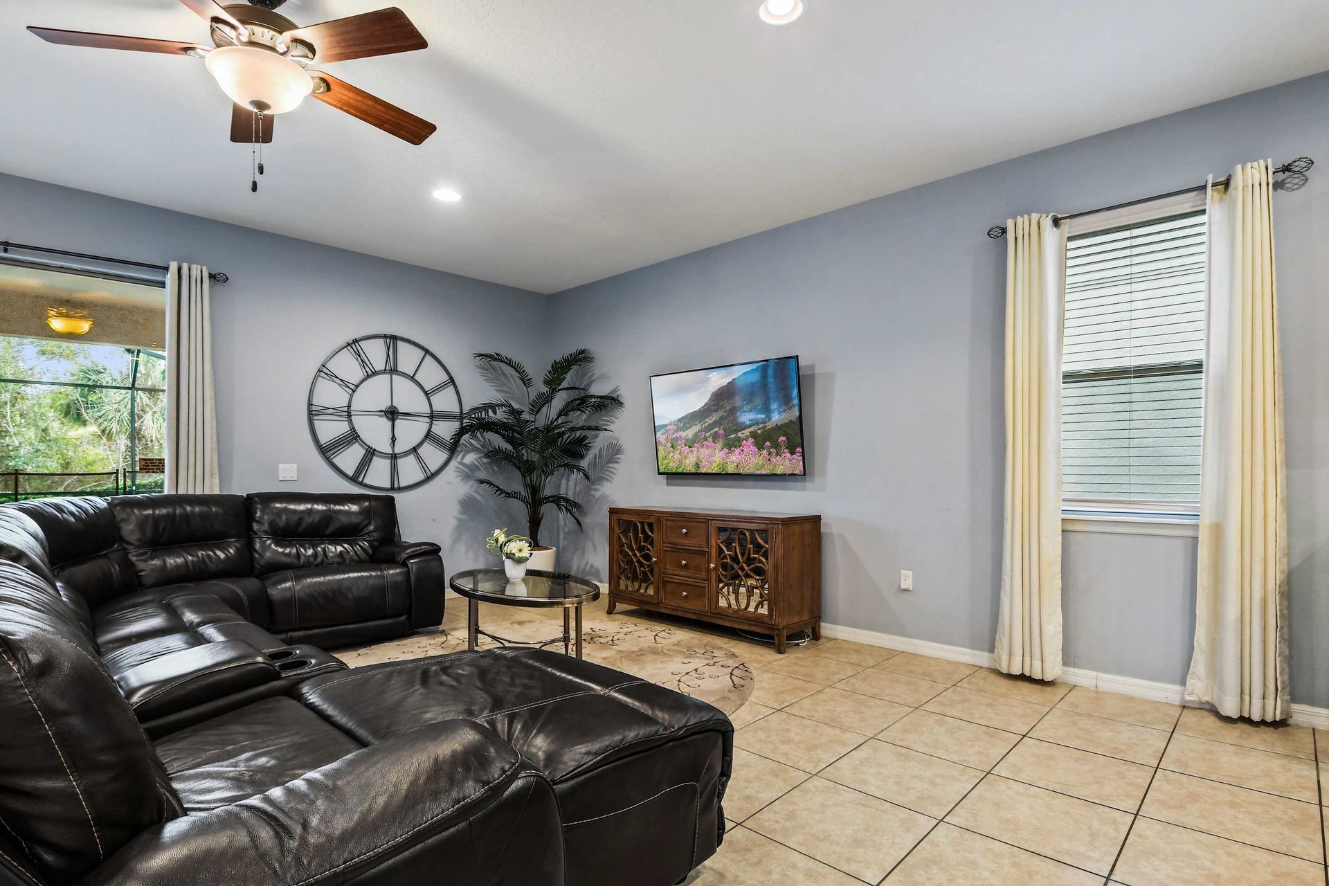 Spacious living area with recliners, pool view, and large TV for cozy evenings.