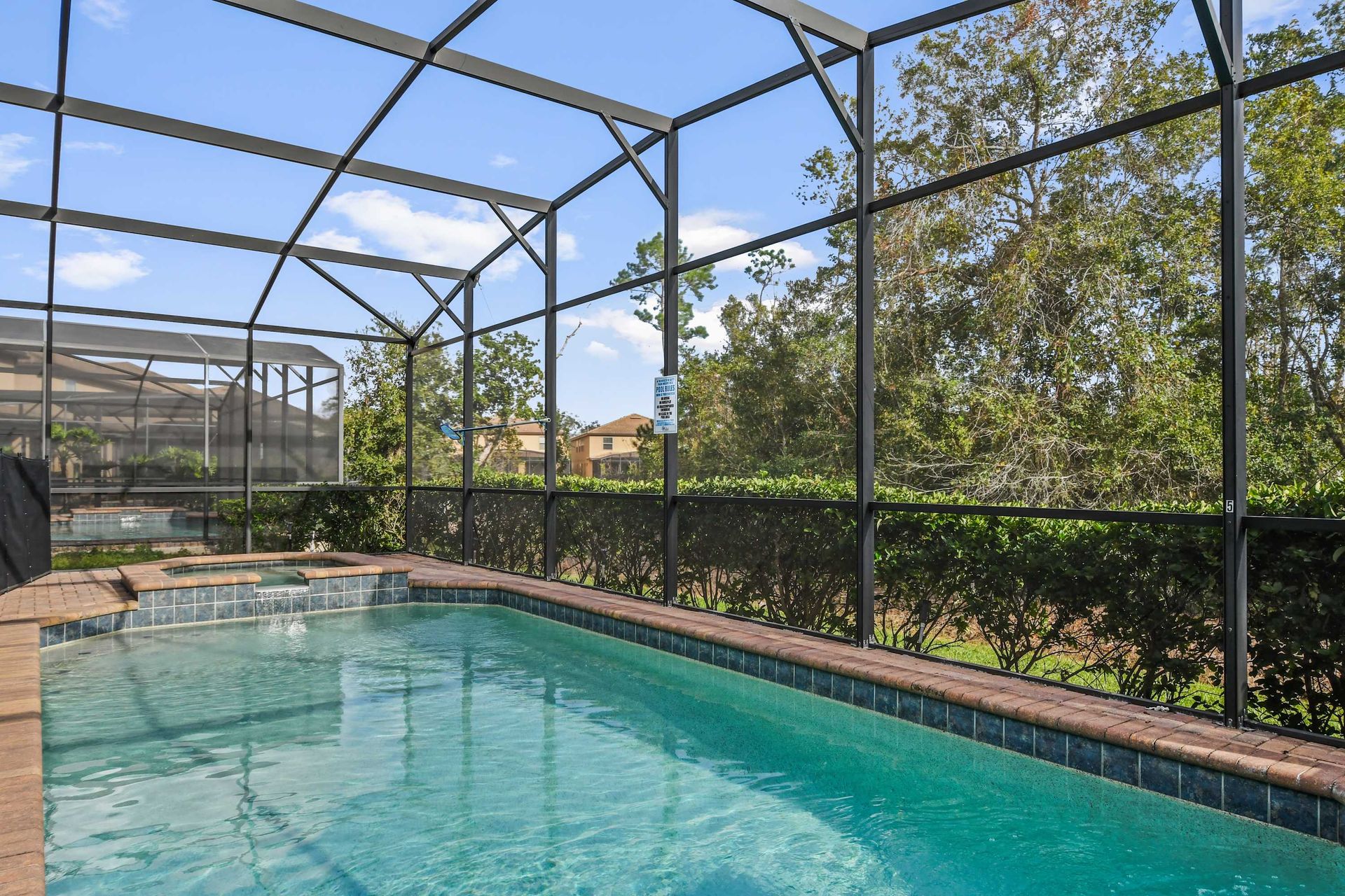 Private screened-in pool and spa with lounge chairs and spacious patio area.