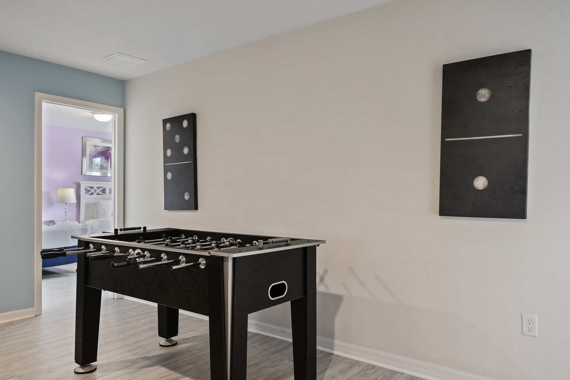 Fun game area with a foosball table, modern art, and bright adjoining bedroom.