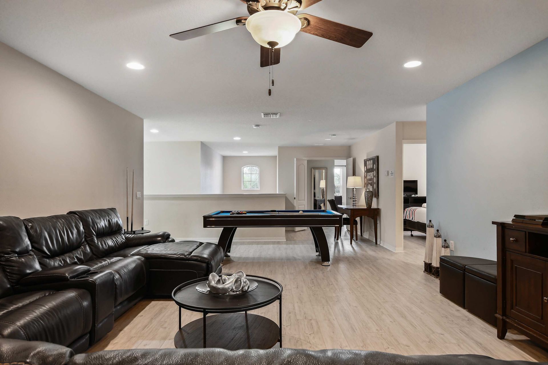 Spacious game room with pool table, leather seating, and modern decor.