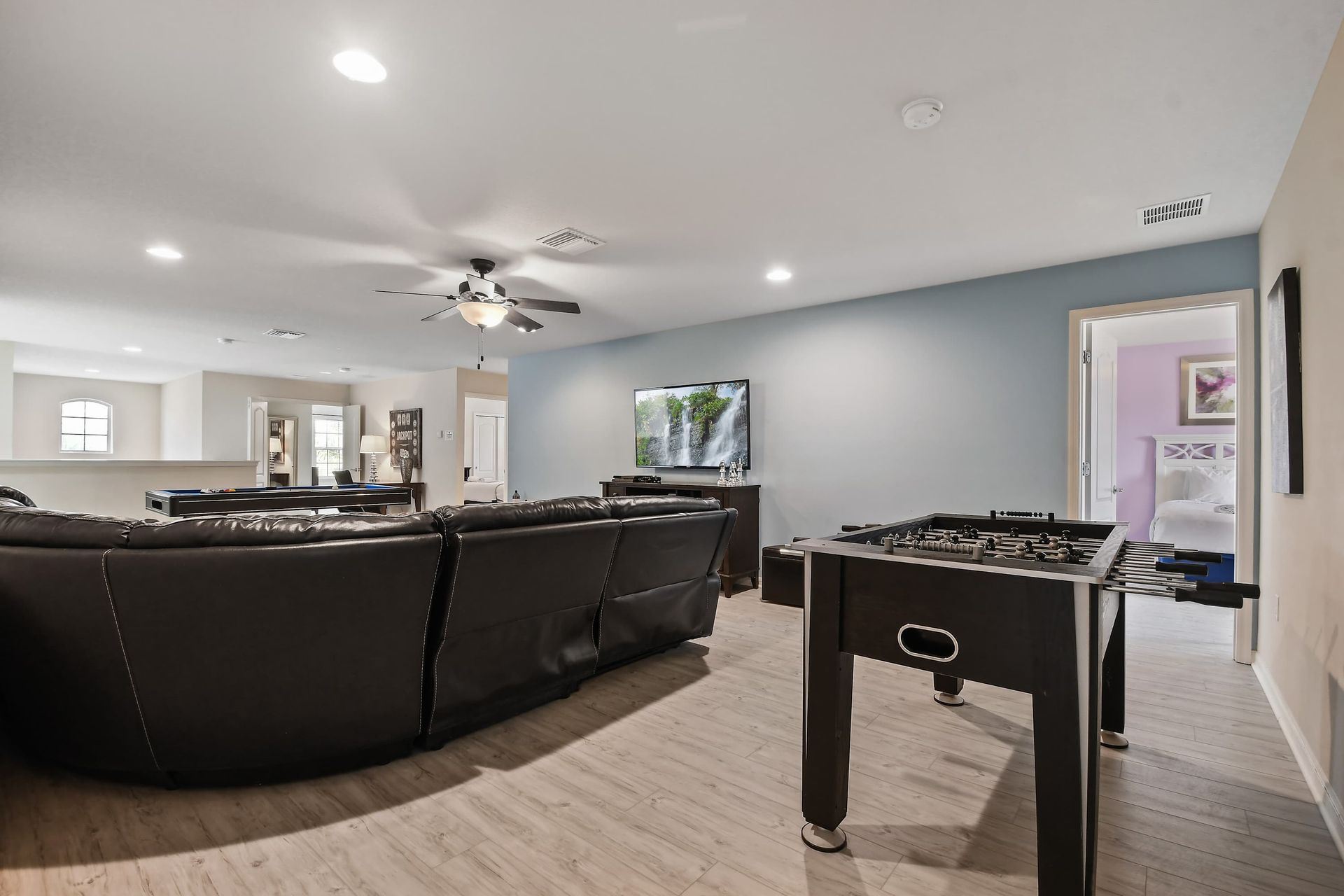 Spacious game room with foosball, pool table, large TV, and comfy seating.