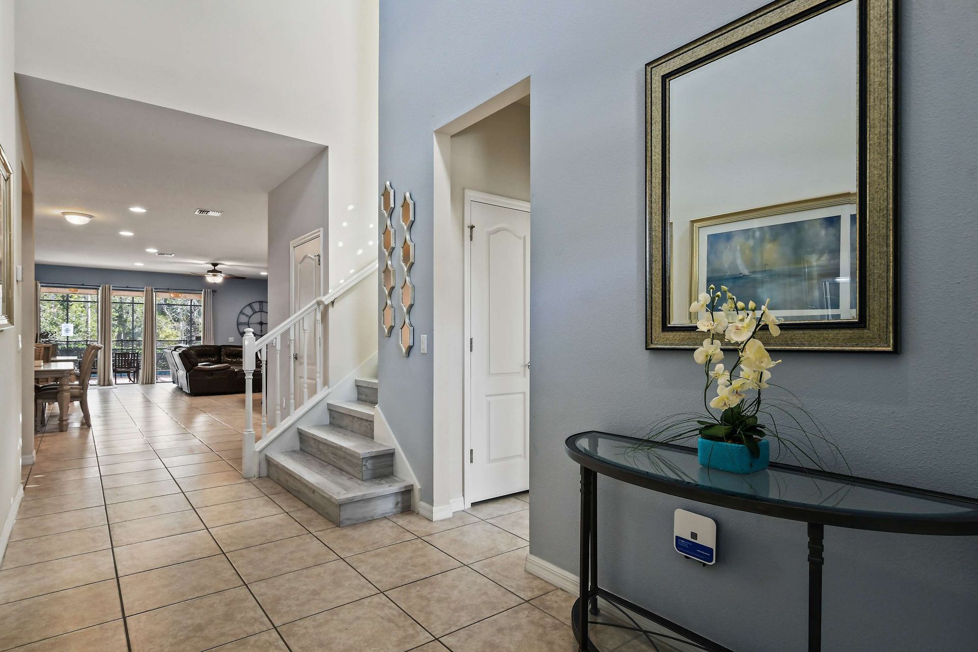 Welcoming entryway with elegant decor, mirror accents, and staircase access.