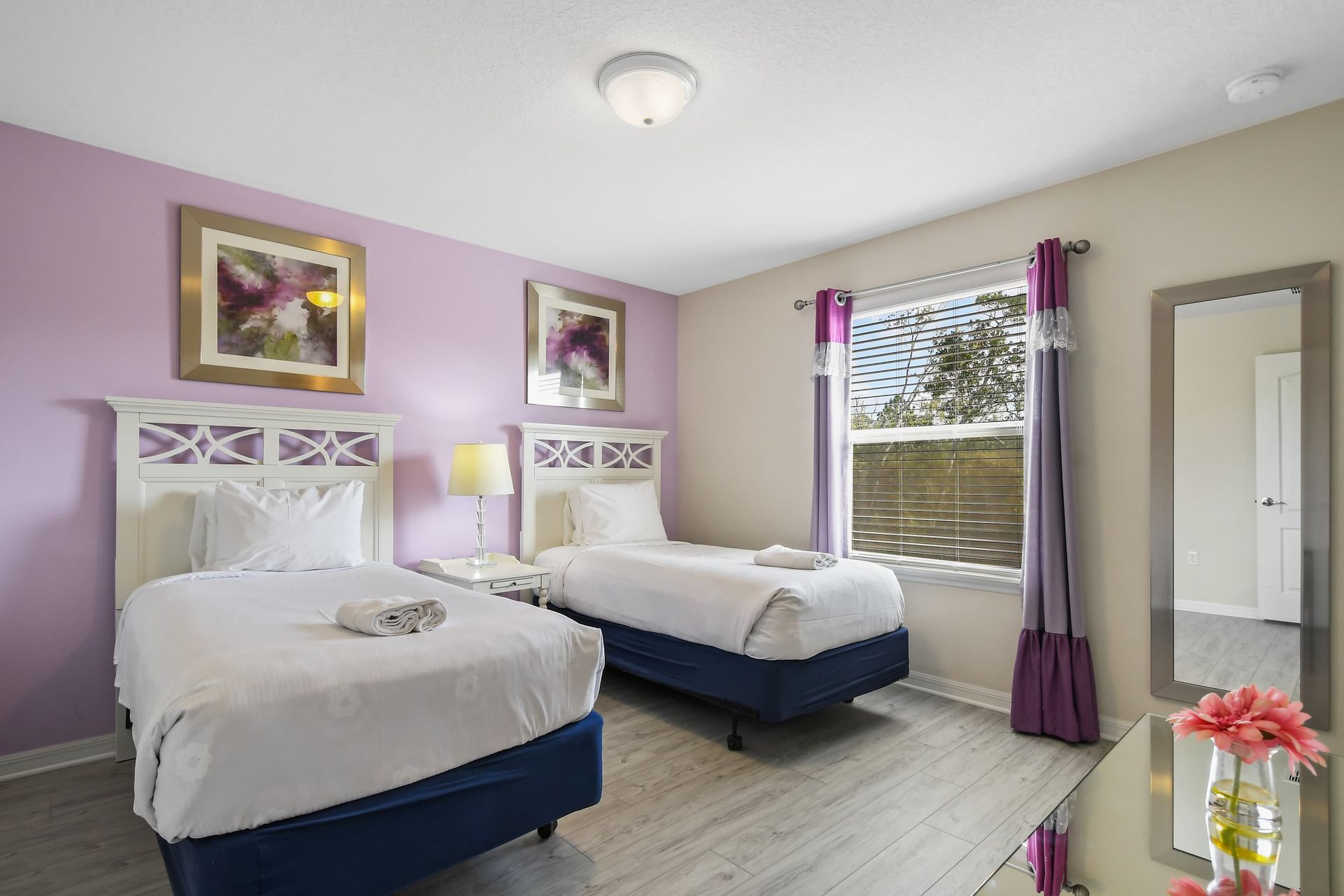 Charming bedroom with twin beds, soft purple accents, and bright natural light.