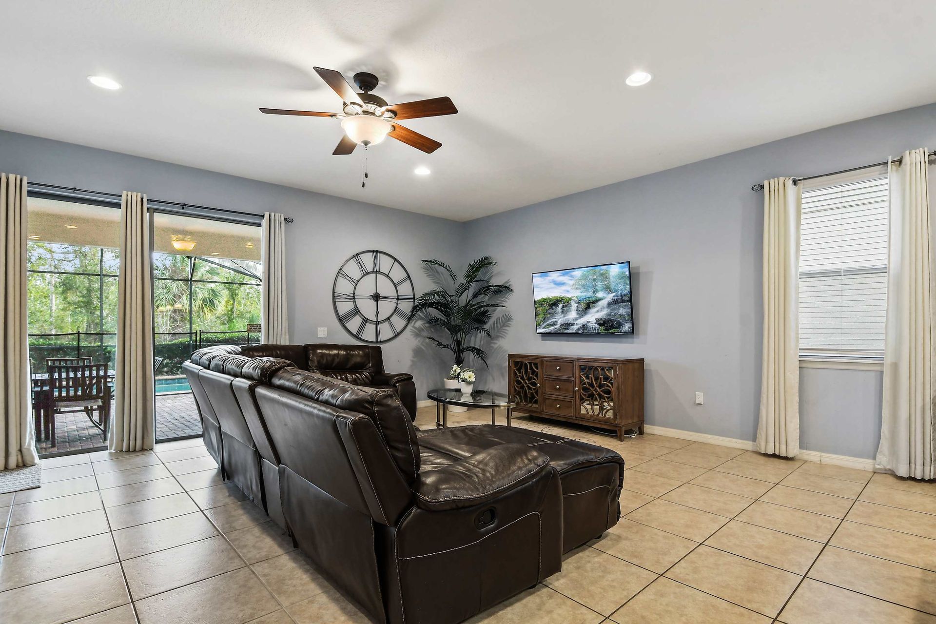 Spacious living area with recliners, pool view, and large TV for cozy evenings.