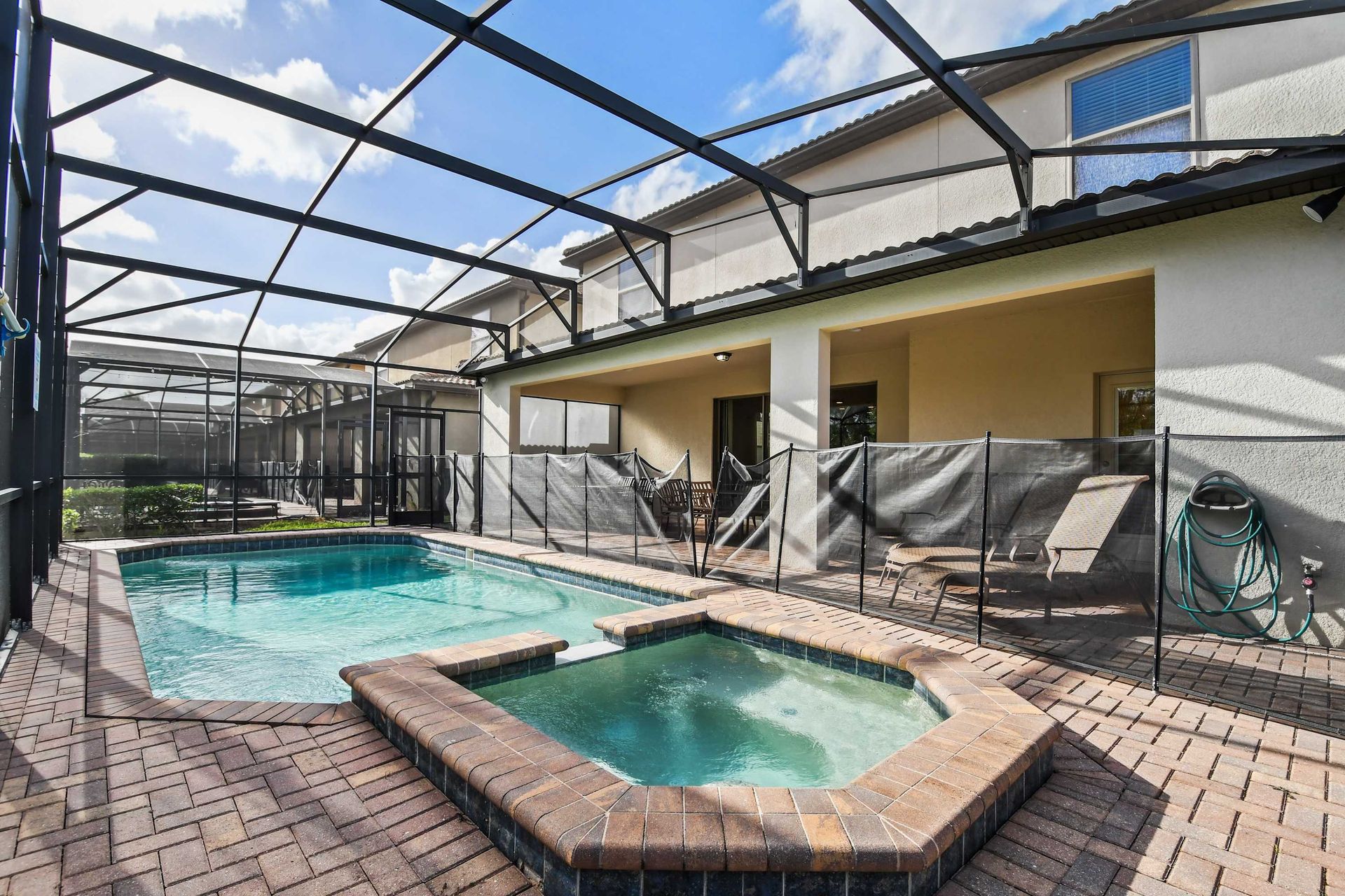 Private screened-in pool and spa with lounge chairs and spacious patio area.