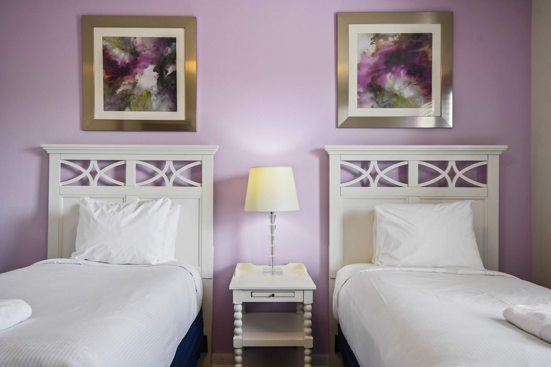 Charming bedroom with twin beds, soft purple accents, and bright natural light.