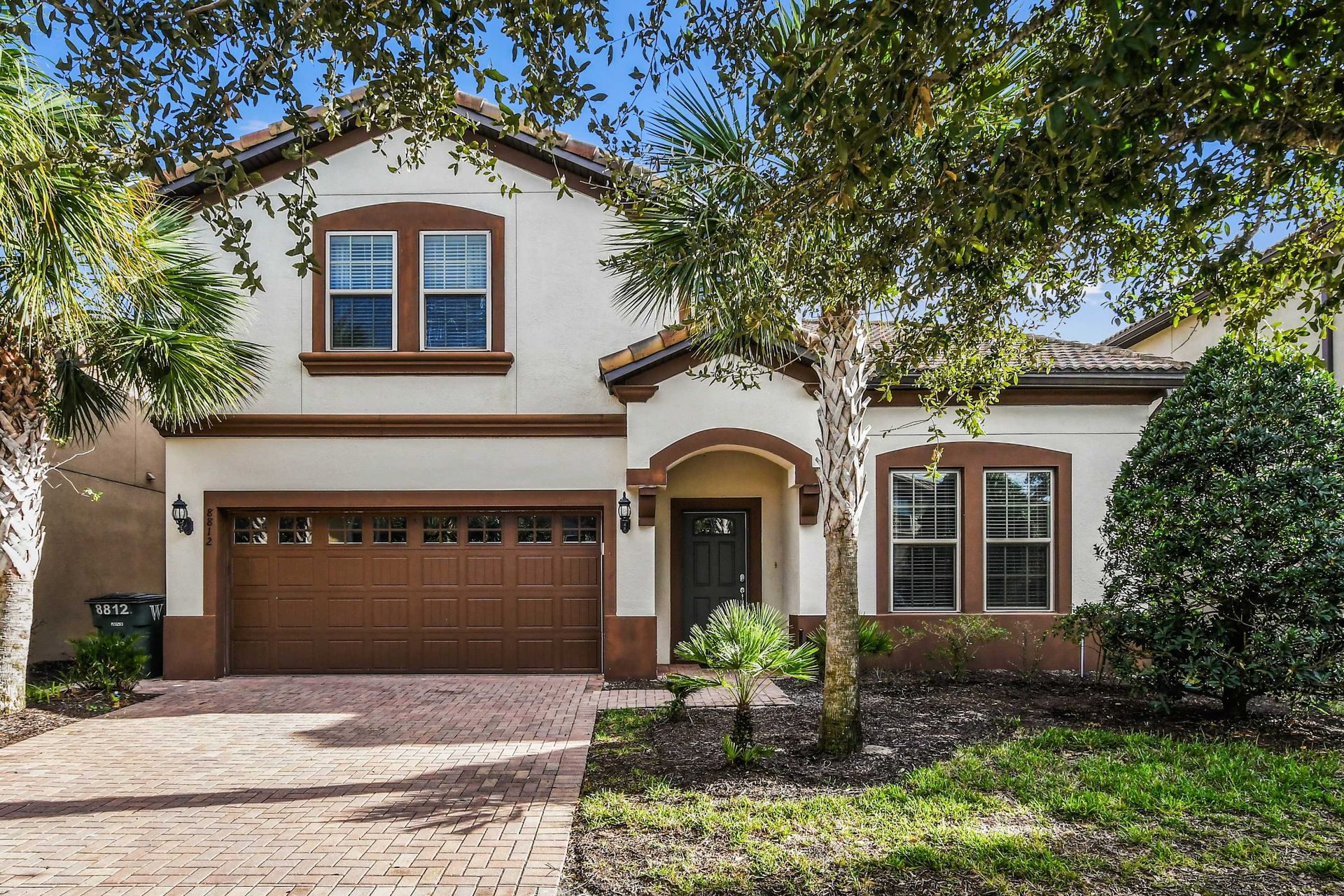 Elegant villa with Mediterranean charm, spacious driveway, and lush landscaping.