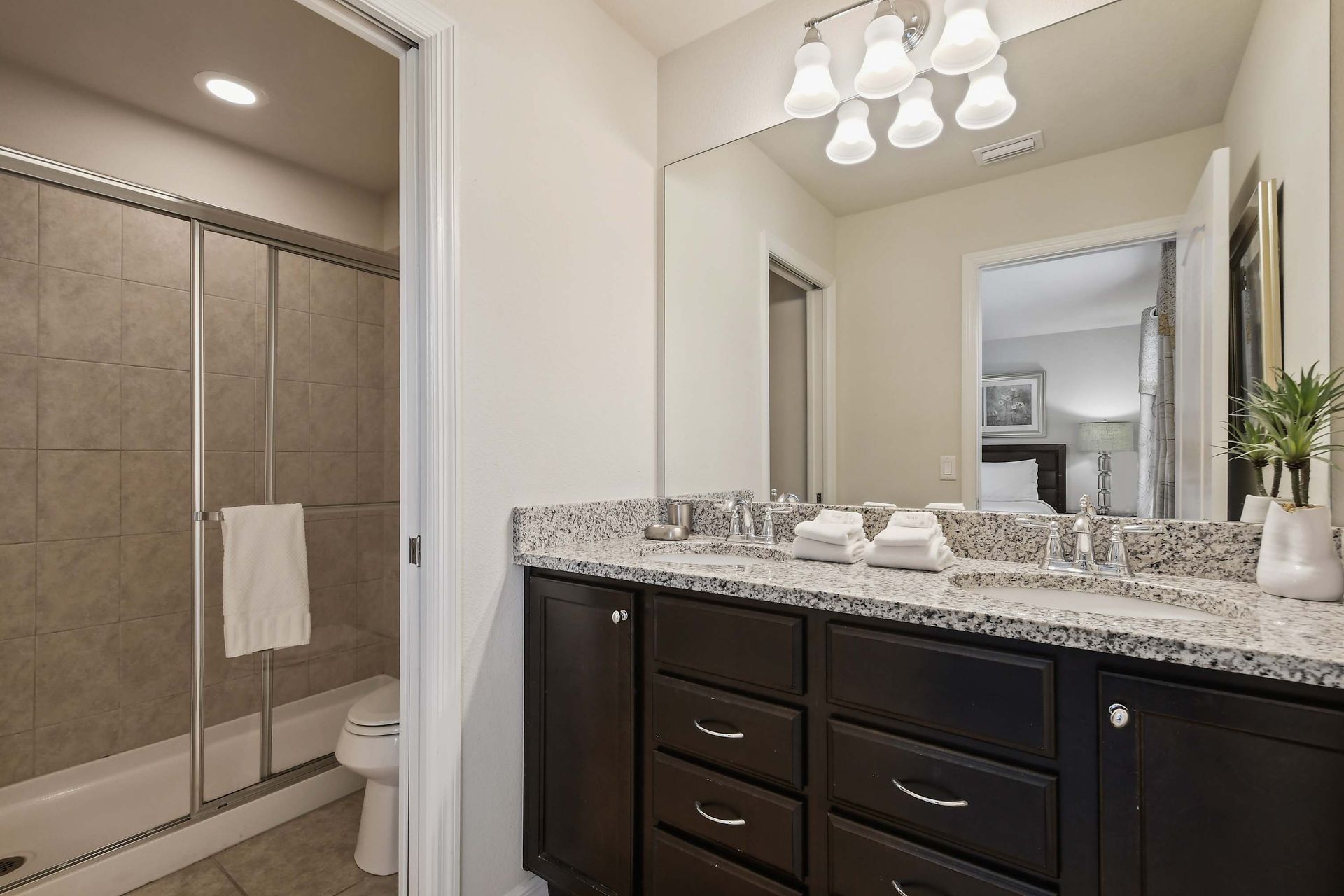 Modern bathroom with granite vanity, tiled shower, and glass enclosure.