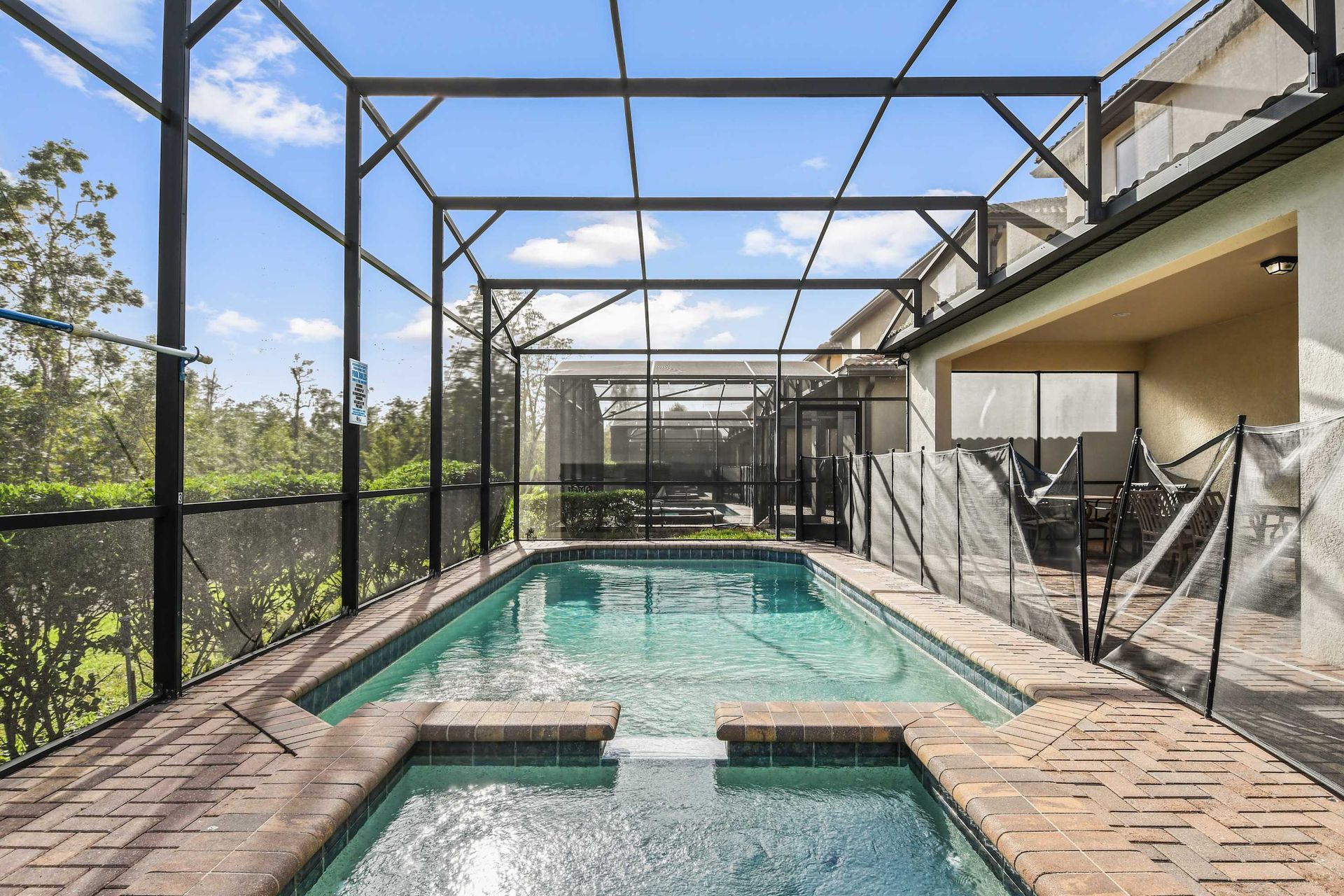 Screened-in pool with spa, peaceful views, and lush greenery for privacy.