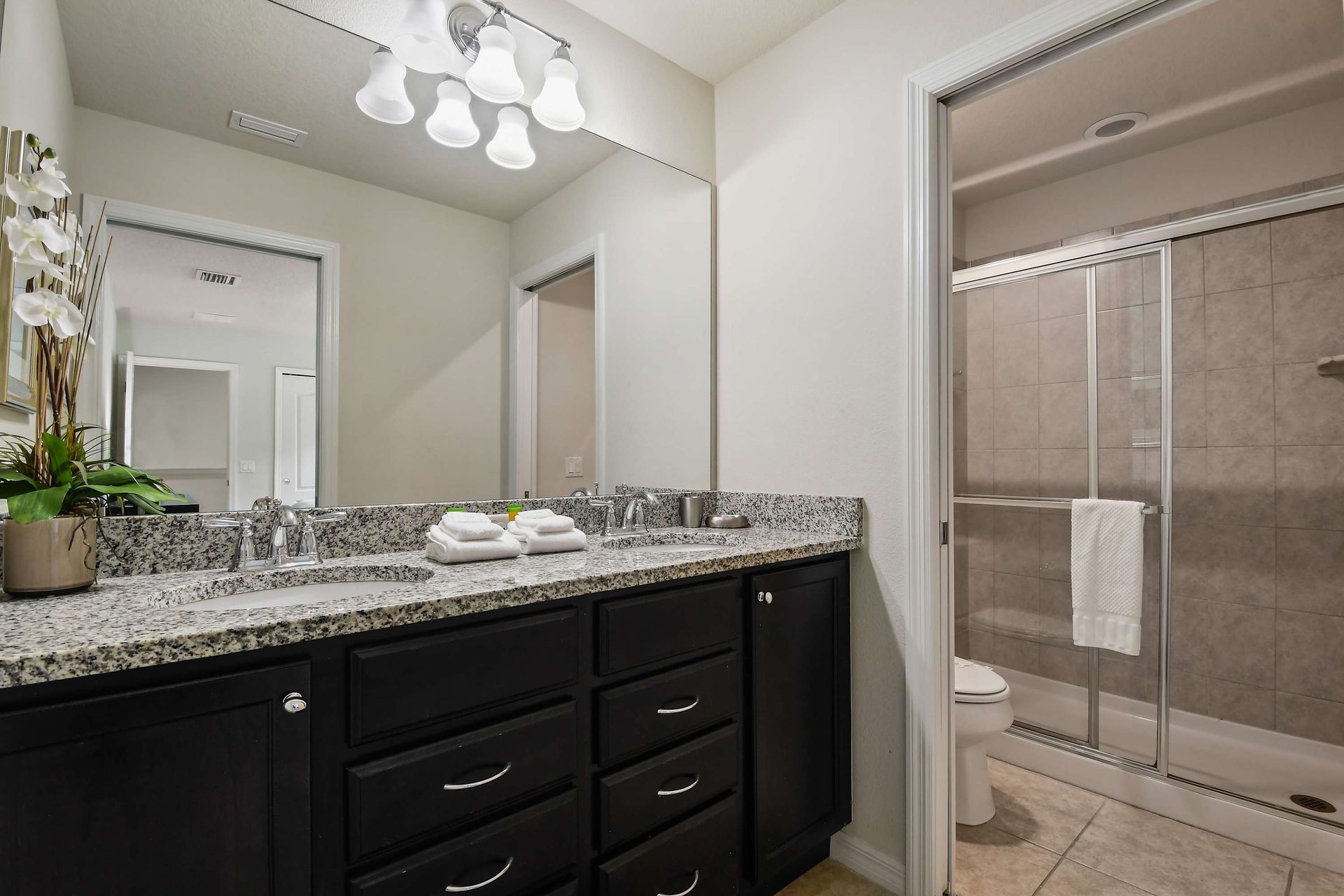 Spacious bathroom with granite counters, dual sinks, and a tiled glass shower.