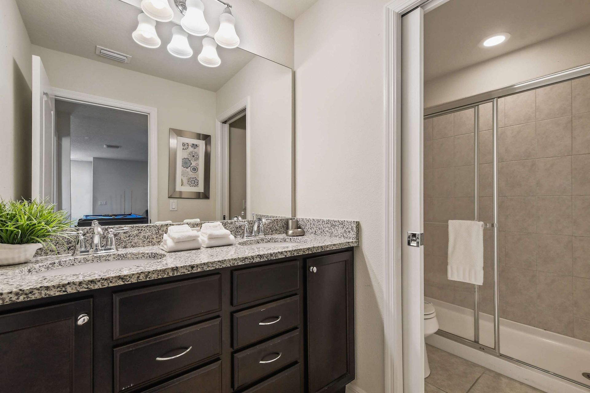 Modern bathroom with granite counters, dual sinks, and a spacious glass shower.