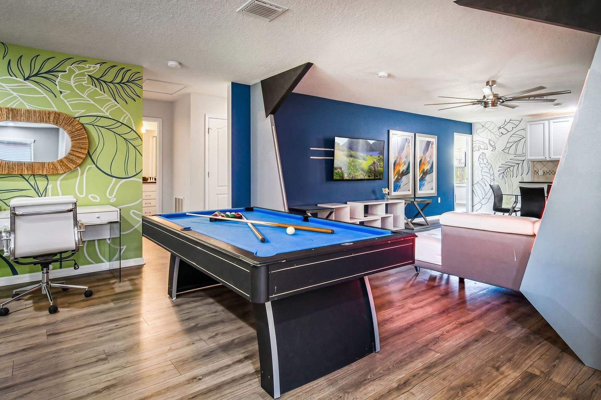 Bright loft space with pool table, desk, bold colors, and tropical wall art.