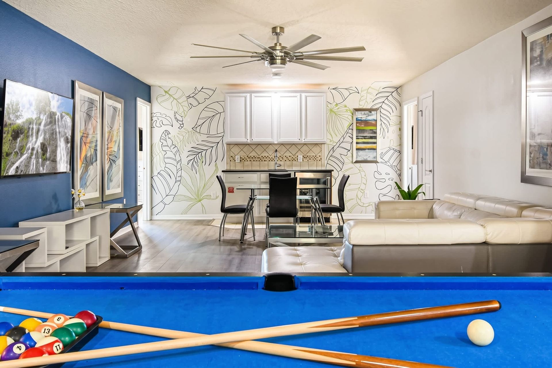 Colorful loft with pool table, TV, modern art, and tropical wall accents.