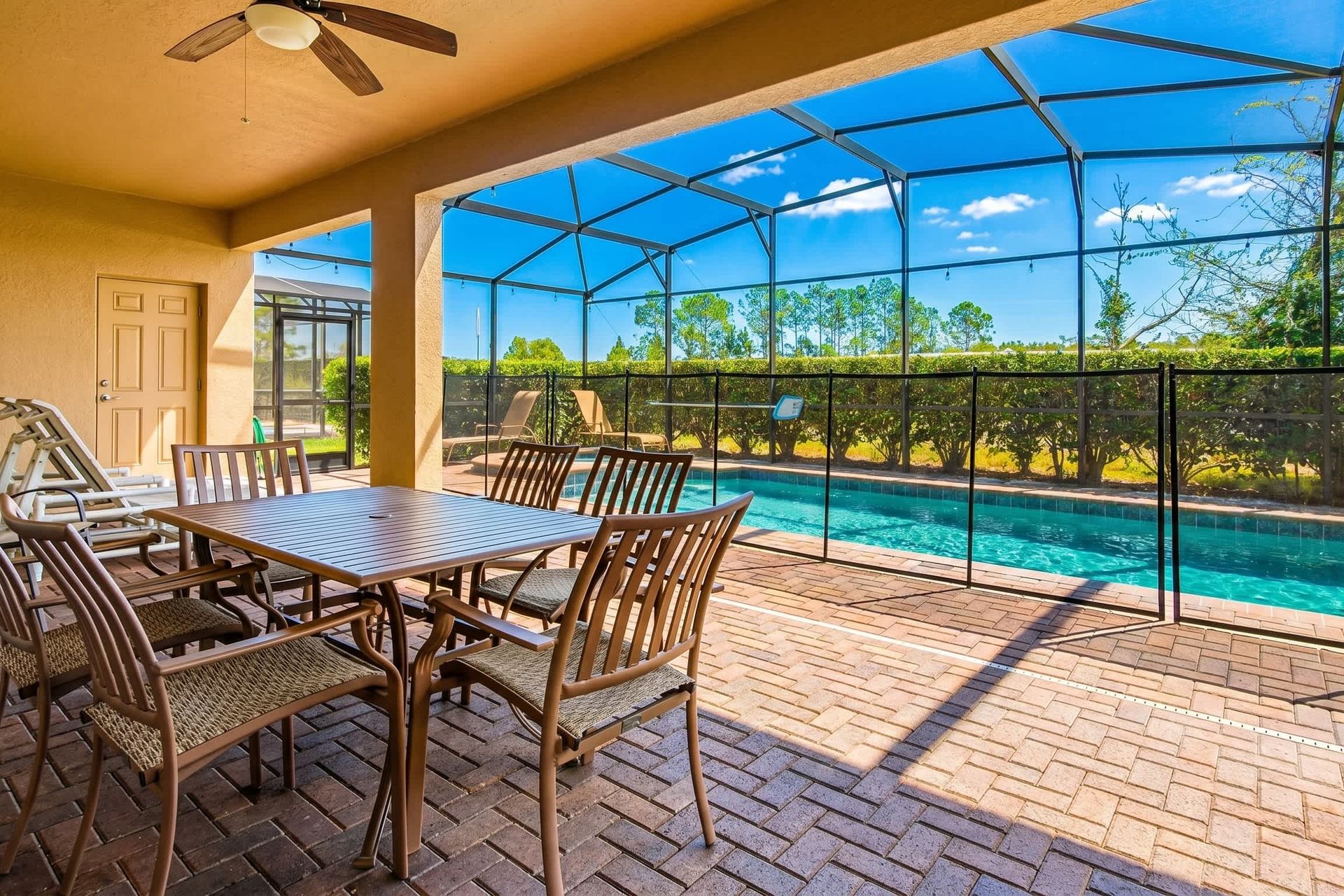 Spacious lanai with dining table, lounge seating, and views of private screened pool.