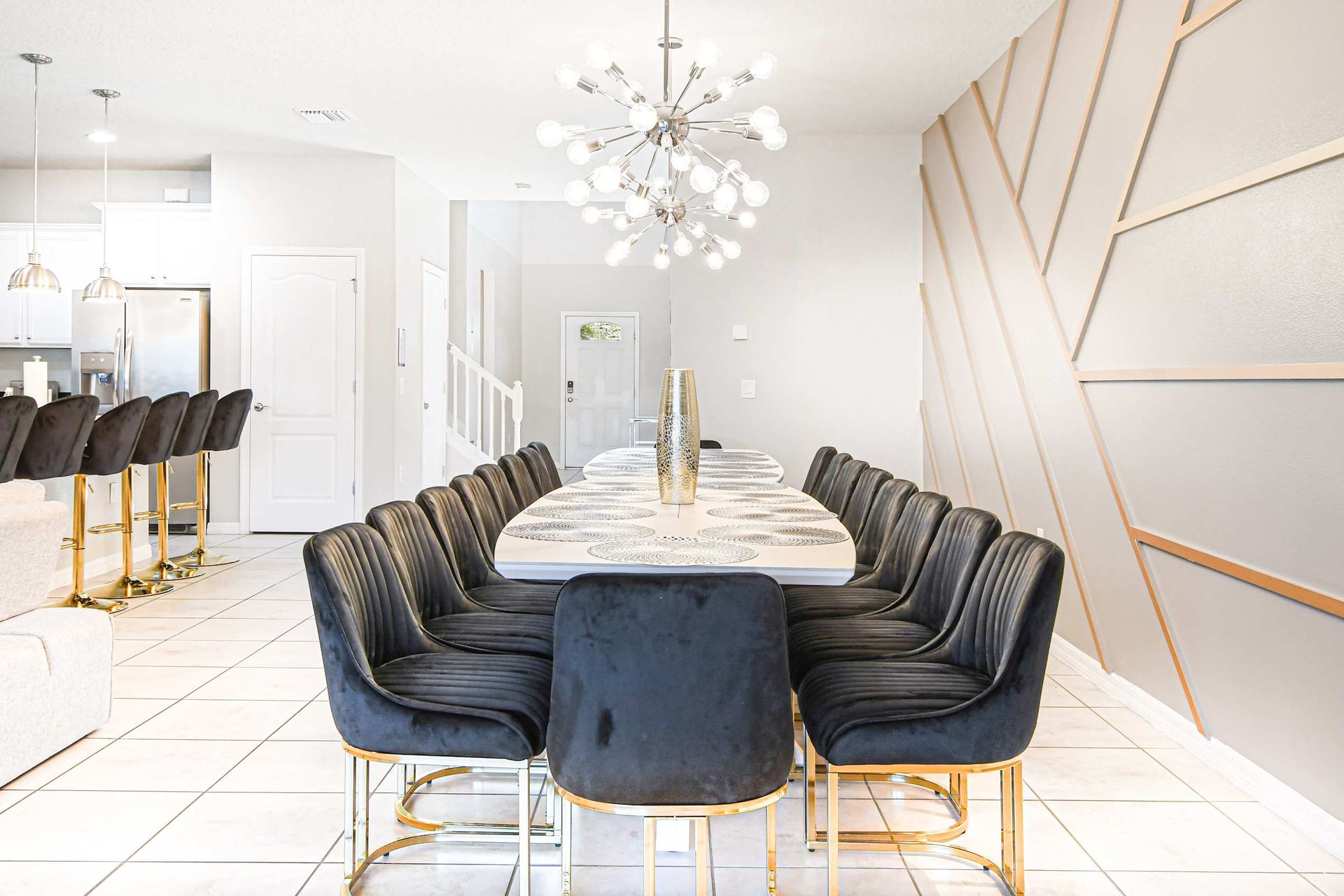 Elegant dining for 14 with bold lighting, modern décor, and a sleek open kitchen.
