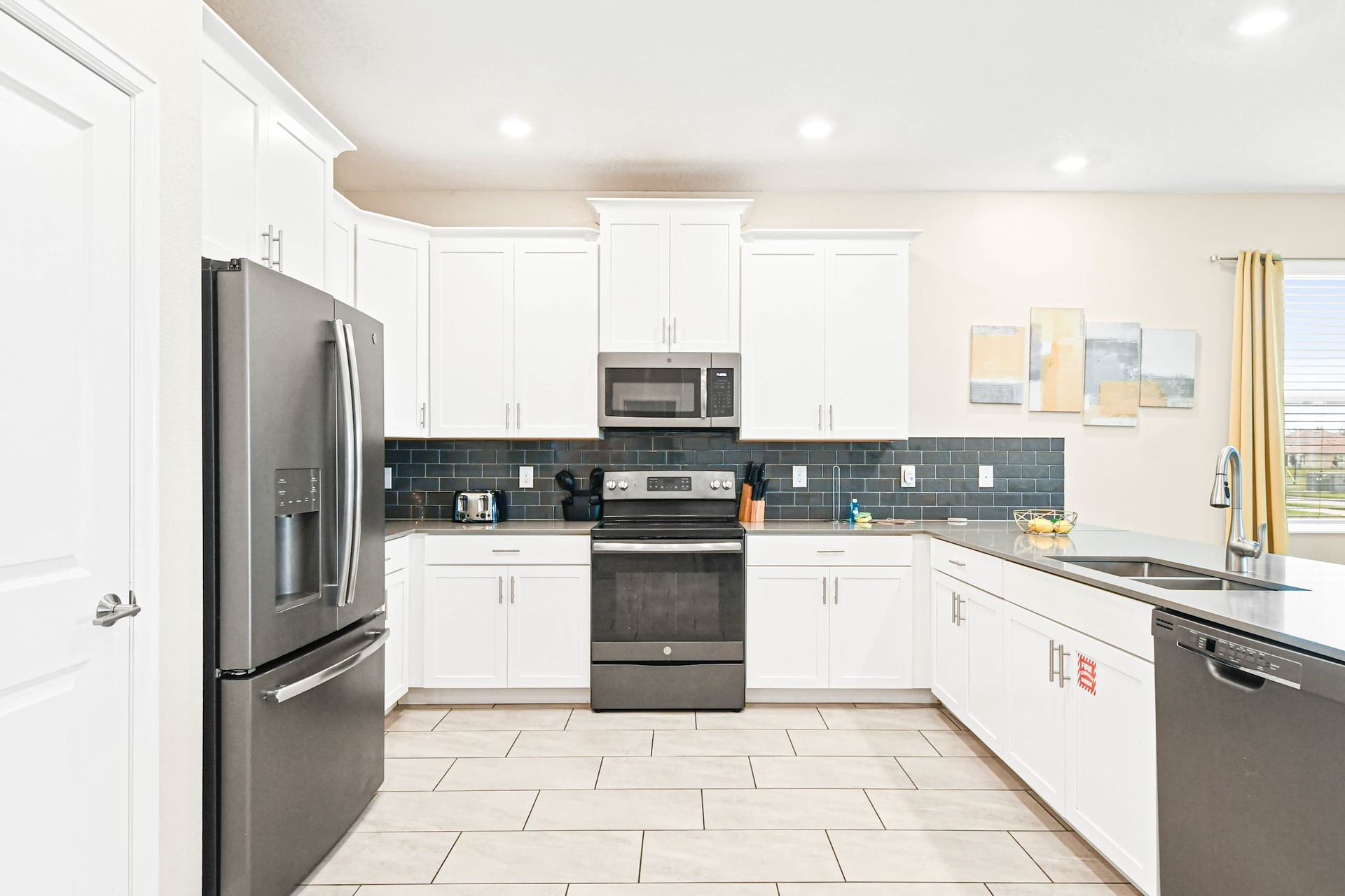 Sleek modern kitchen with stainless steel appliances, white cabinets, and a stylish backsplash.