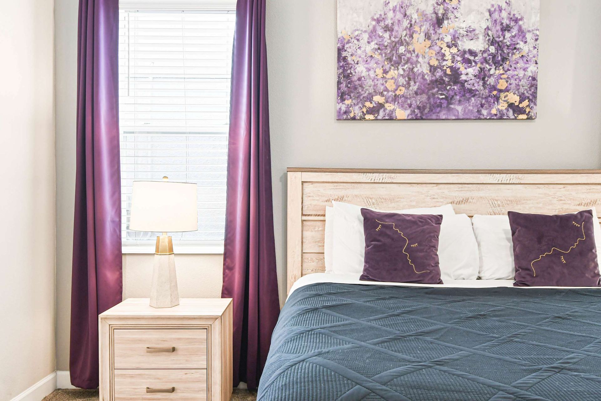 Elegant bedroom with purple accents, cozy bedding, and modern decor for a luxurious, restful retreat.