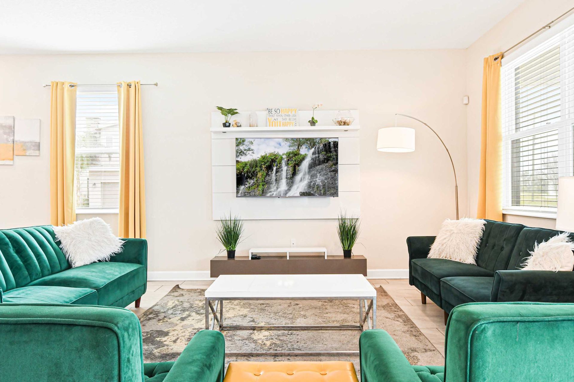 Bright living room with lush green sofas, vibrant decor, and cozy ambiance for perfect relaxation.