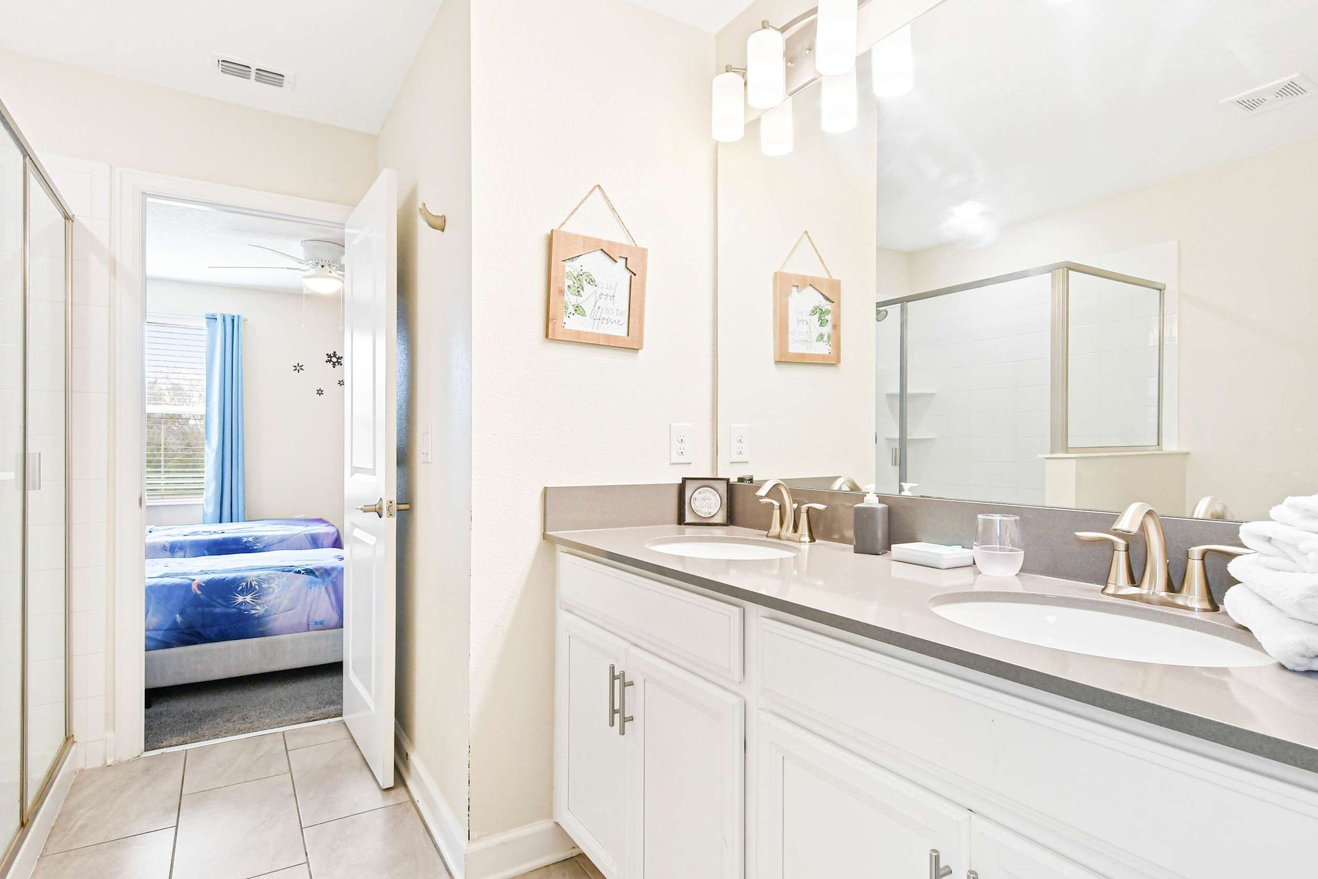 Bright and inviting bathroom with dual sinks, modern fixtures, and a glimpse of a themed bedroom!