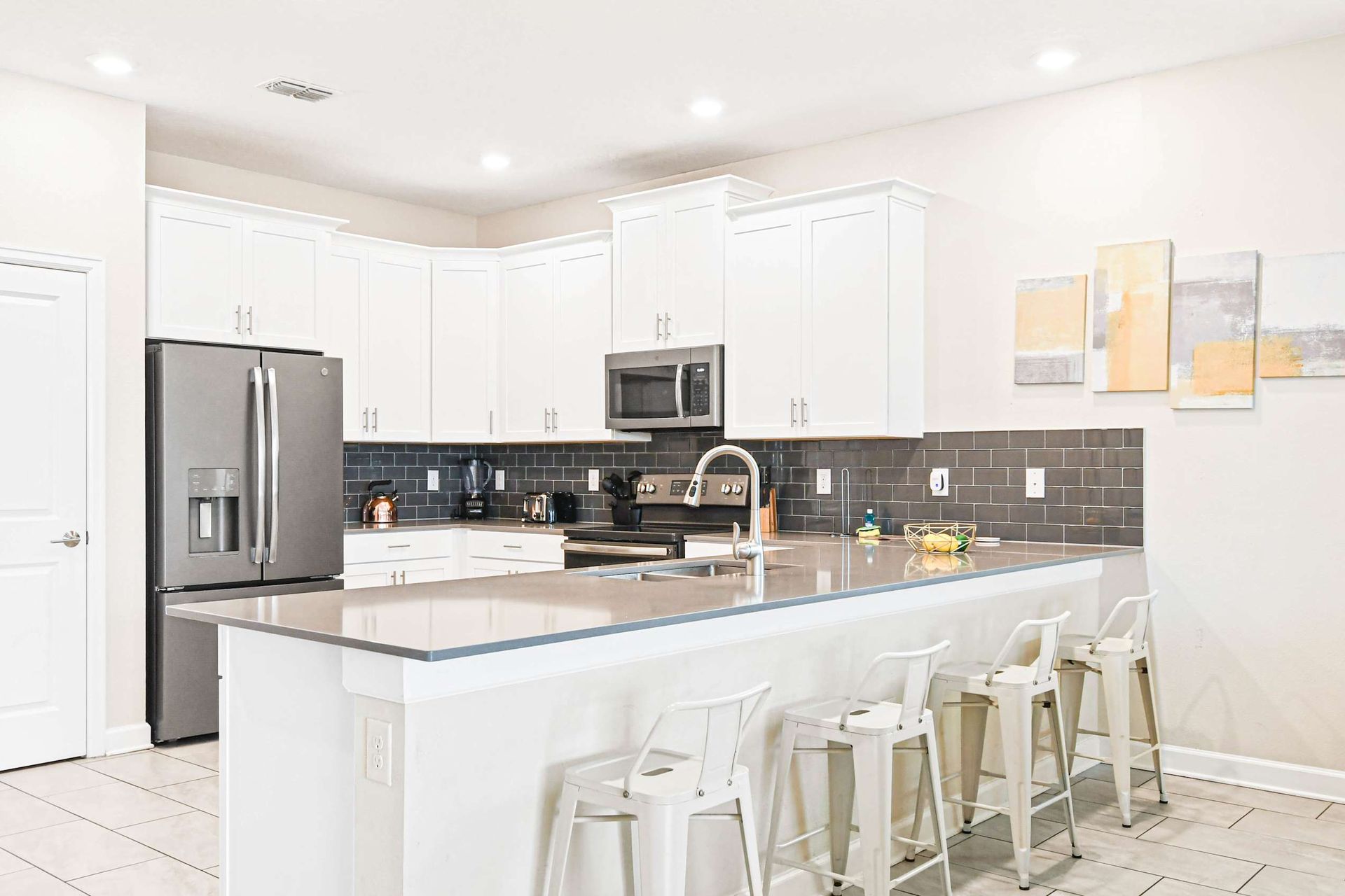 Bright modern kitchen with sleek appliances, a large island, and a stylish backsplash.