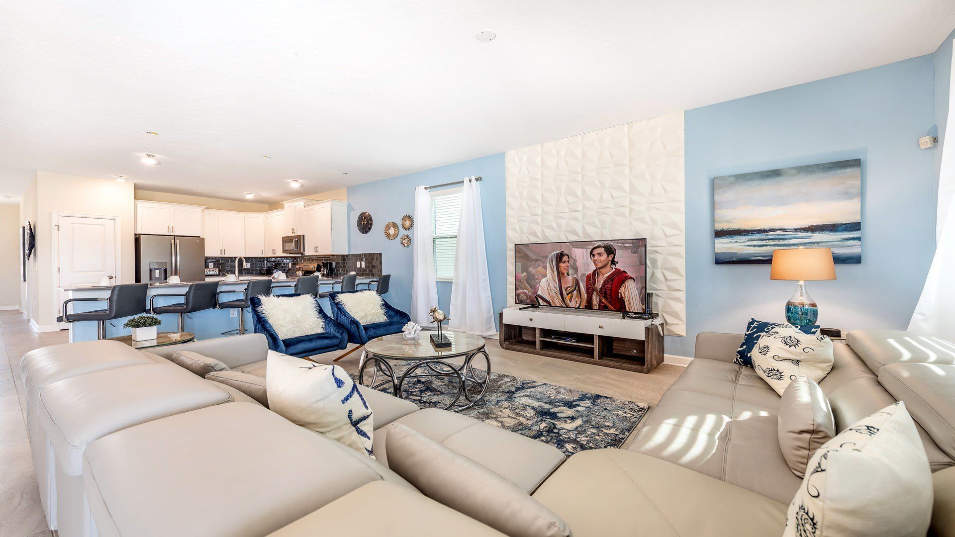 Spacious living area with cozy seating, modern decor, and open kitchen