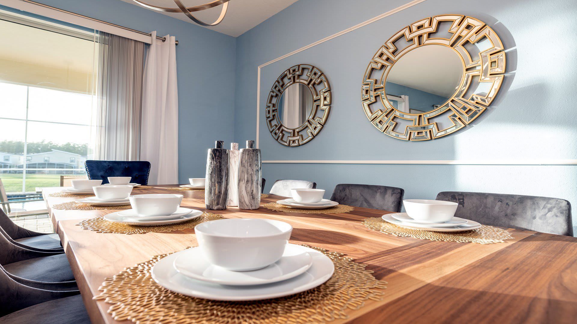 Elegant dining area with gold accents, blue walls, and modern decor.