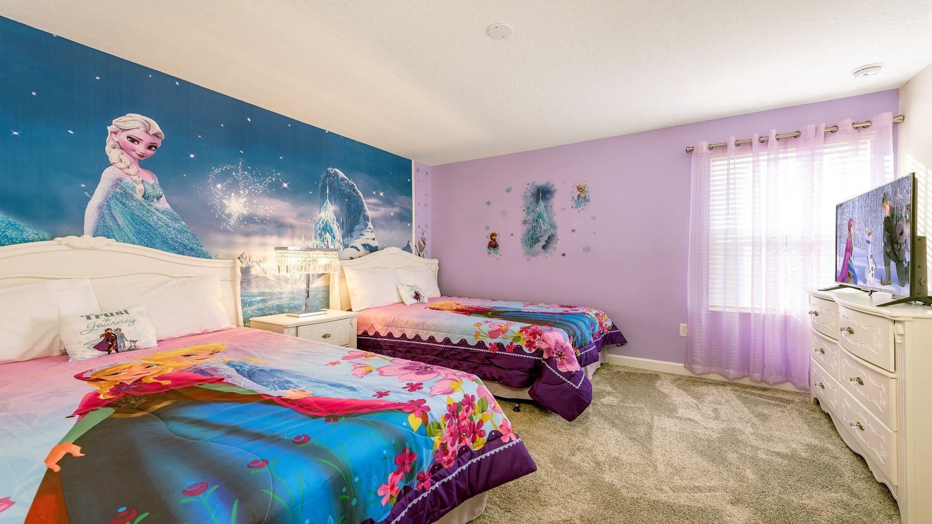 Frozen-themed bedroom with twin beds, vibrant decor, and TV setup